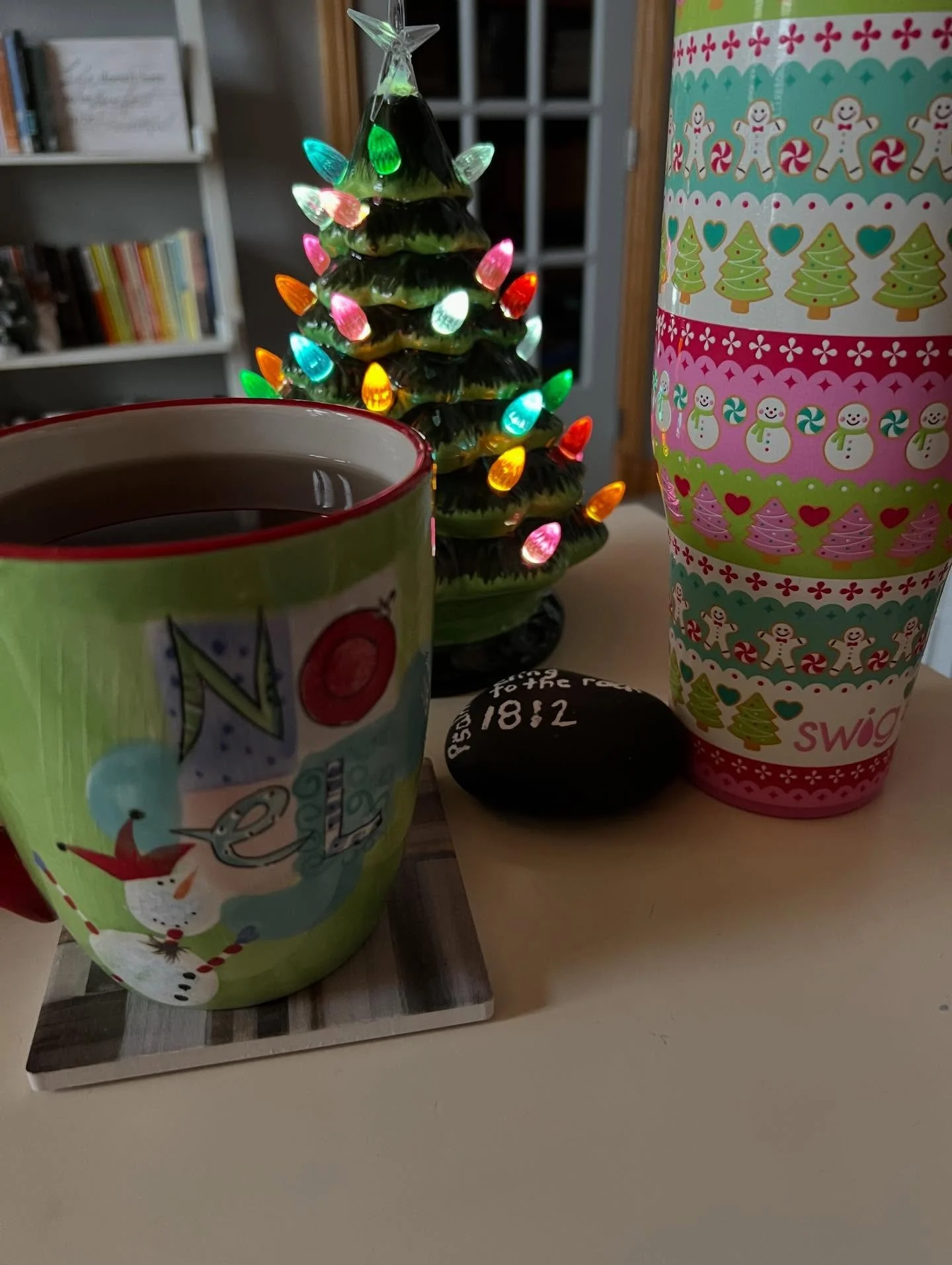 This is the corner of my desk with my fun, but old, mug that has my morning tea in it. There&rsquo;s a festive water cup that I bought a couple years ago. It encourages me to keep hydrated. There&rsquo;s a ceramic tree I bought this year that looks l