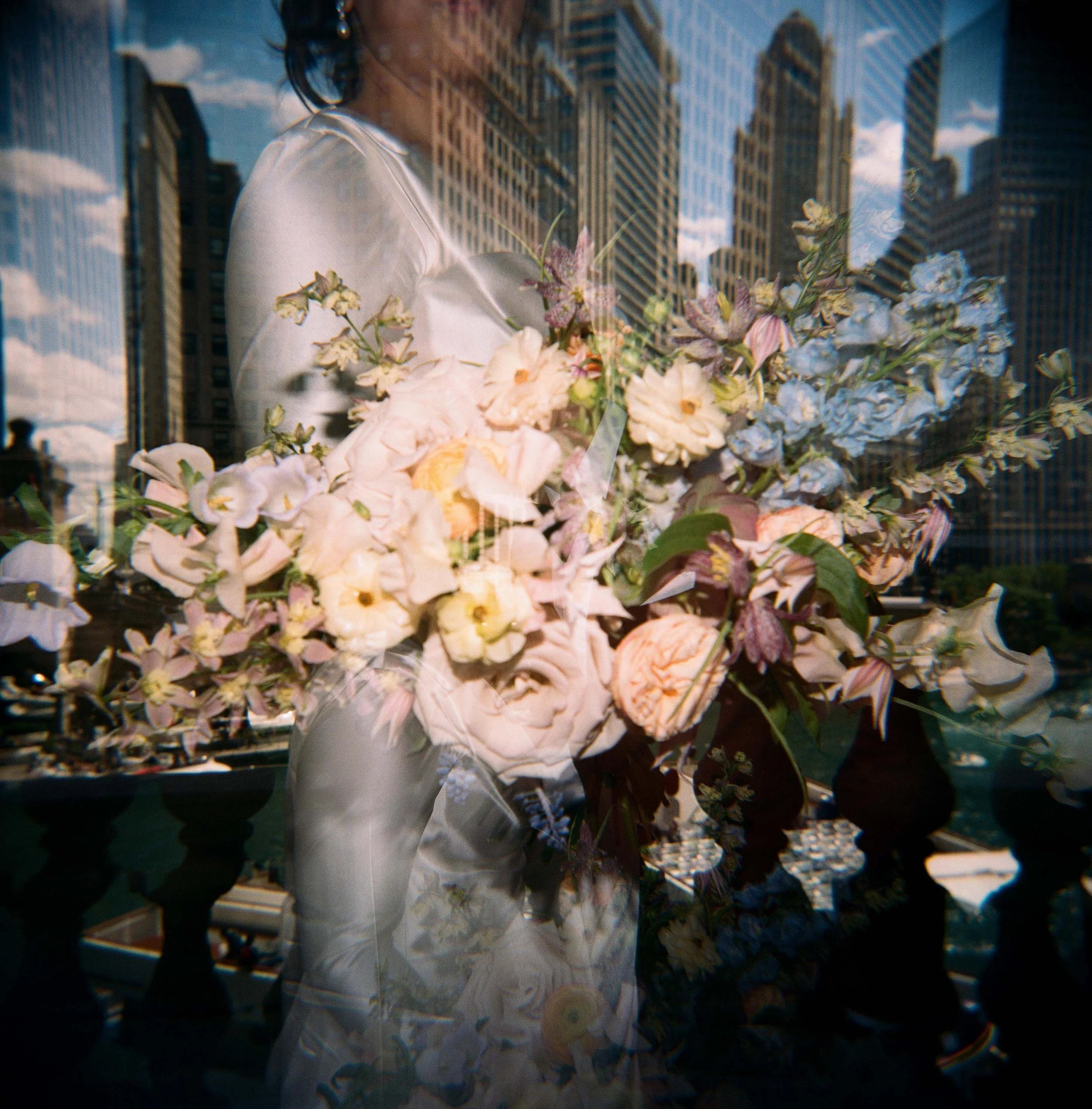 film photo of bride with a bouquet layered over a city skyline