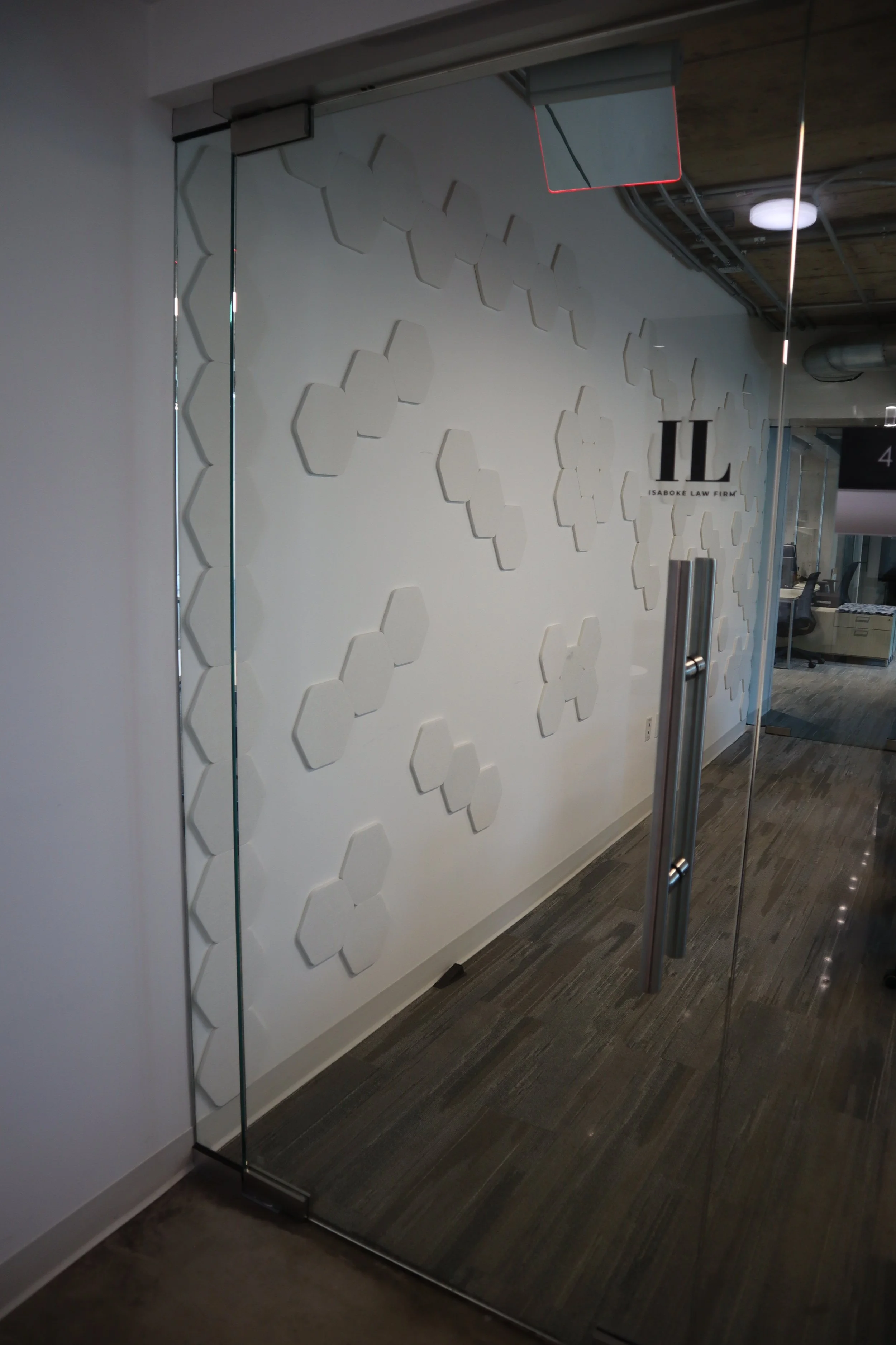 Glass door with a black and white logo of Ilabore Law Firm on frosted design on the wall behind it.
