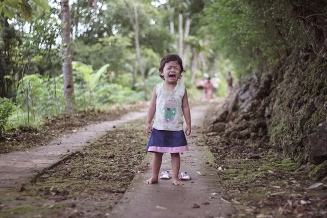 child standing in the middle of a pathway crying