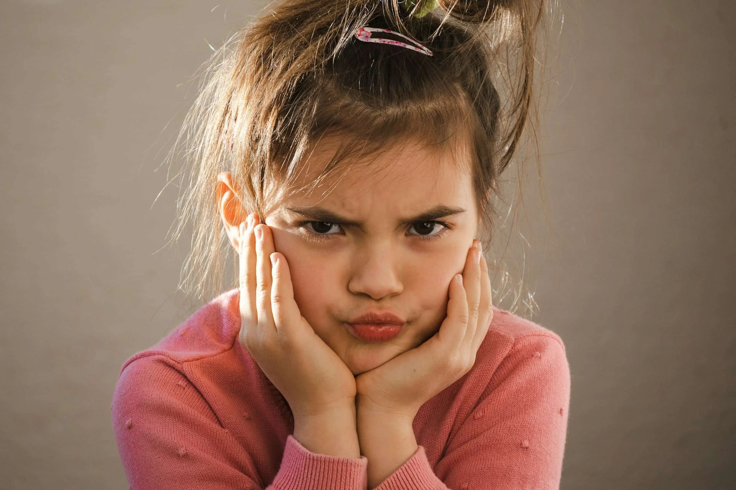 photo of child looking unhappy with hands on cheek