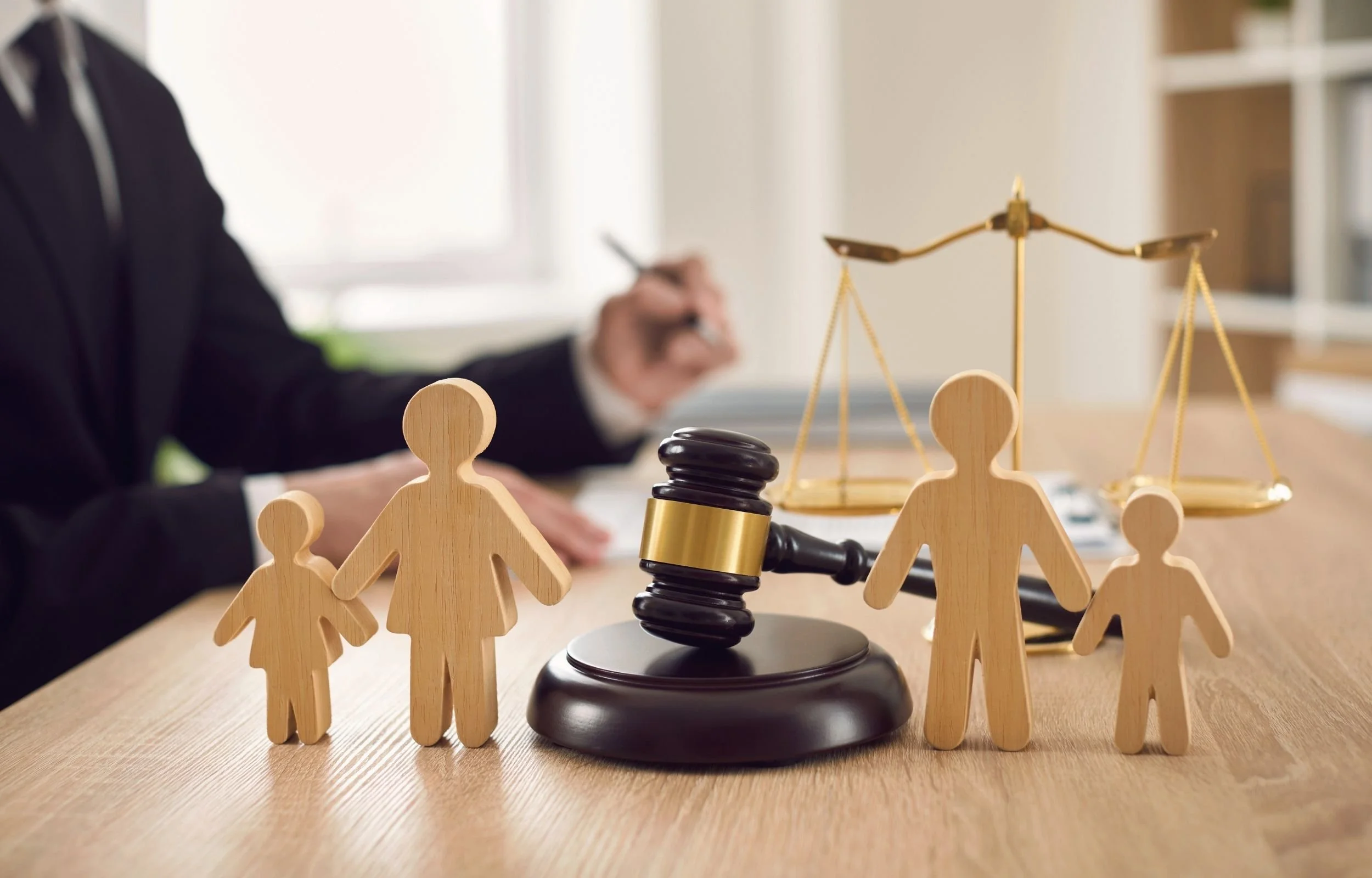 Parent and child figures separated by a judge’s gavel and scales of justice, representing co-parenting, separation, divorce, and the impact of family changes on children.
