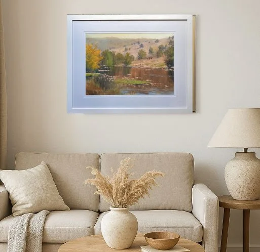 Framed oil painting Macquarie by Frank Hodgert, showing a calm river, autumn trees, and distant hills. Displayed in white mat and frame with soft natural lighting