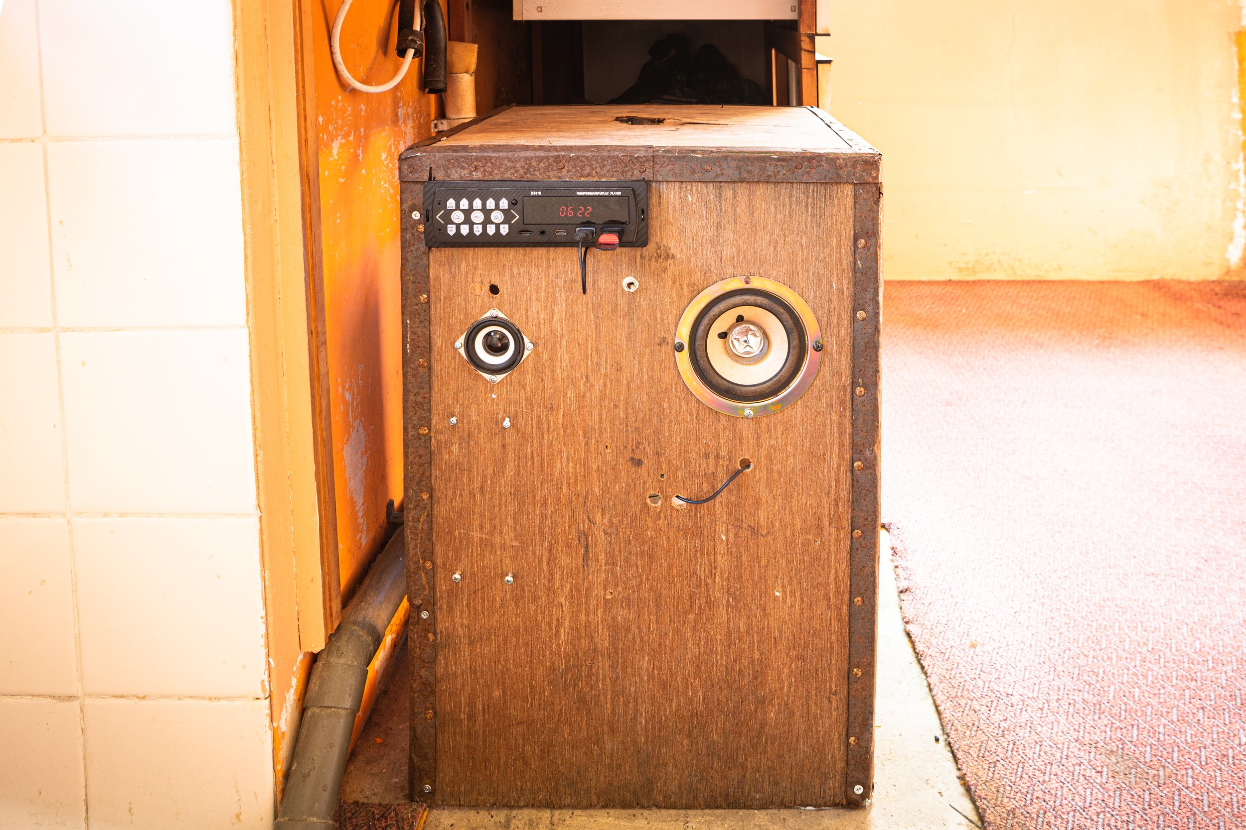 tea chest with car speakers and car sterero shown, it sits under a kitchen counter