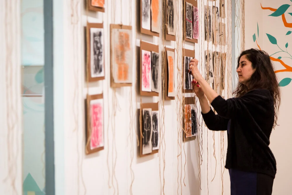 PFP Art Facilitator, Dima Karout, putting the finishing touches to Roots and Branches, an exhibition of our participants' work at the Museum of Croydon in 2019.