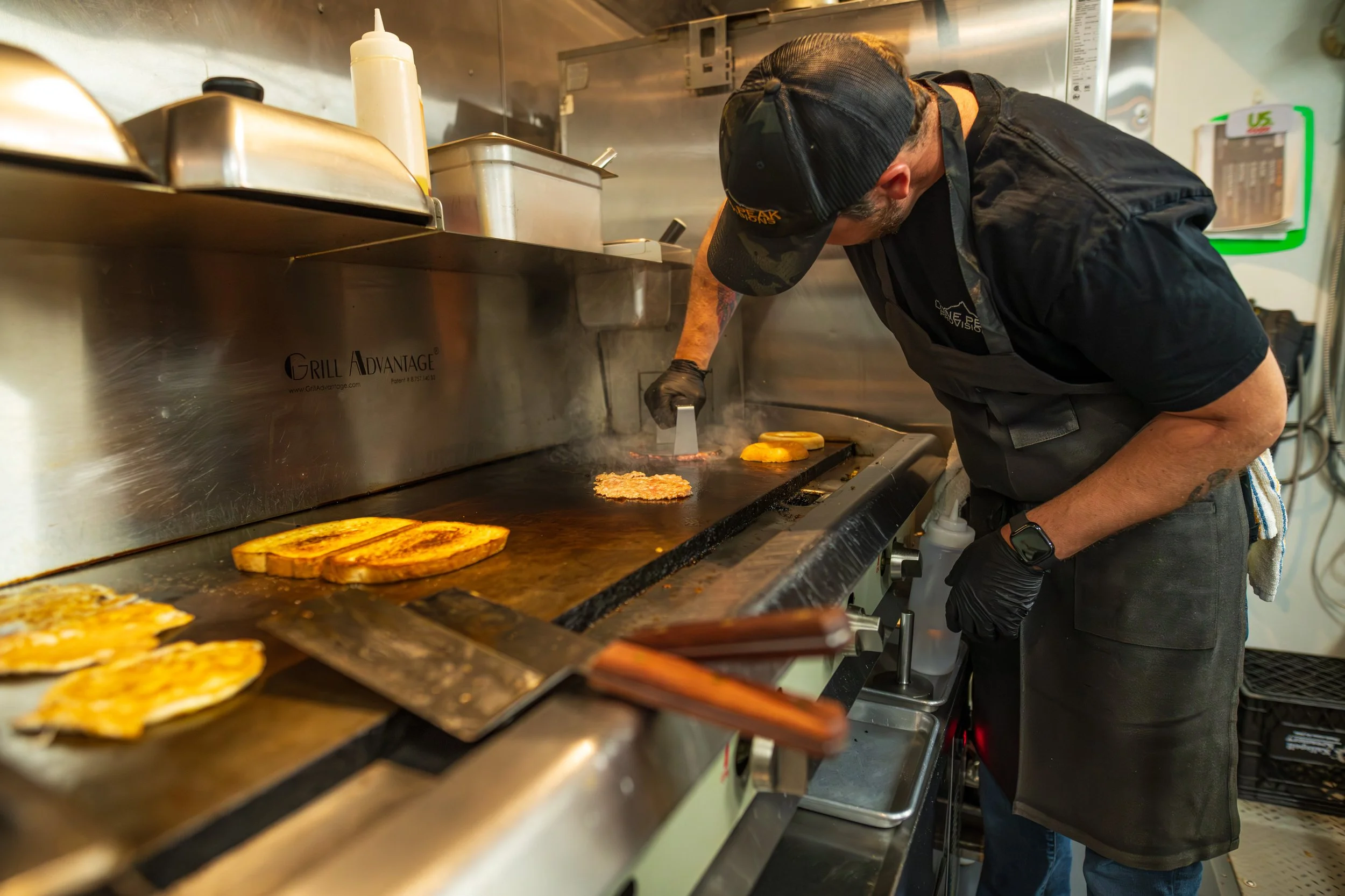 Chef Jeremy smashing sausage patties for the breakfast sandwiches