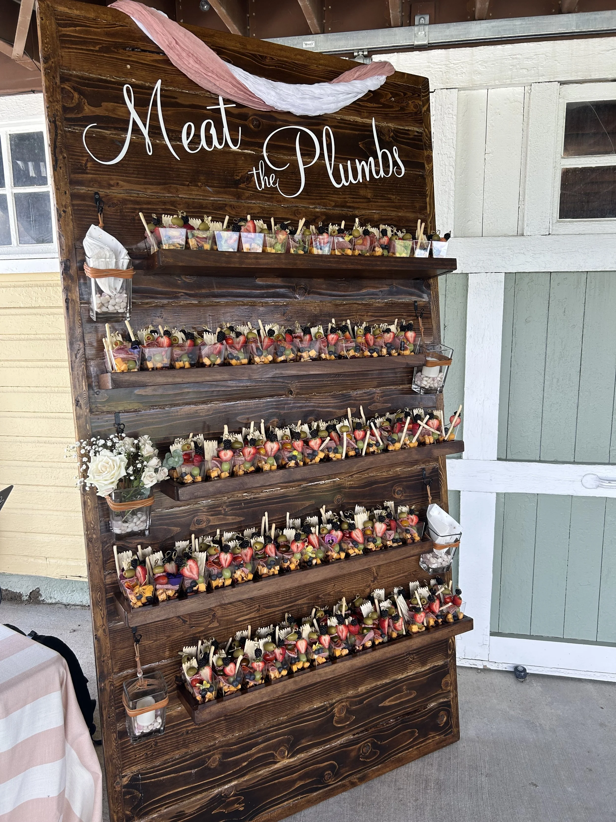 Individual single-serving charcuterie cups lined up on a self-serve grazing wall at a catered event by Lone Peak Provisions in Bozeman, Montana — a fun and interactive appetizer option for weddings, corporate events, and private parties.