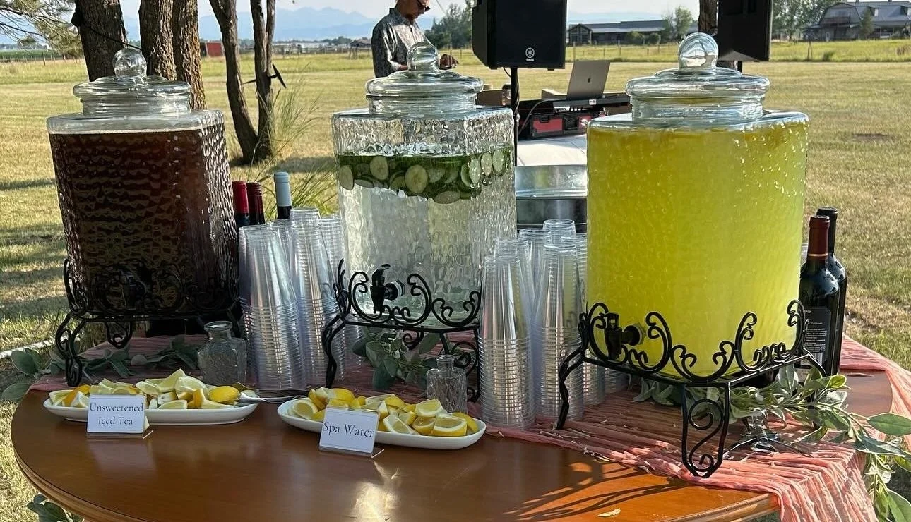 A self-serve hydration station featuring lemonade, iced tea, water, and sliced lemons set up for a catered event by Lone Peak Provisions in Bozeman, Montana.