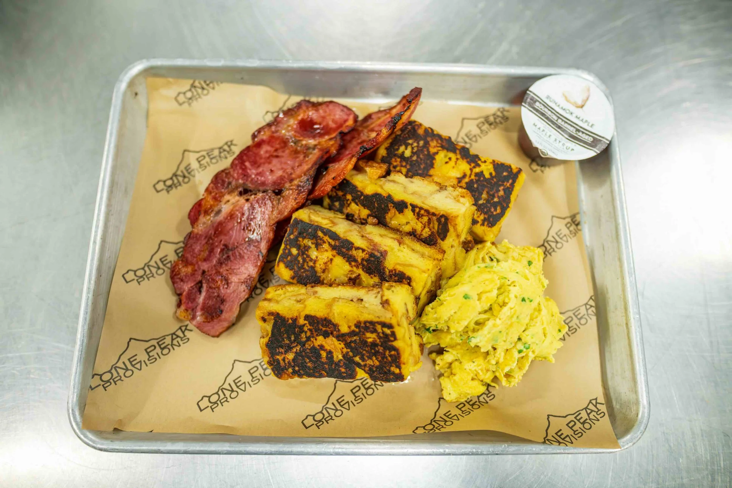 French toast plate with donut french toast, thick cottage bacon and scrambled eggs. Breakfast menu option at Lone Peak Provisions.