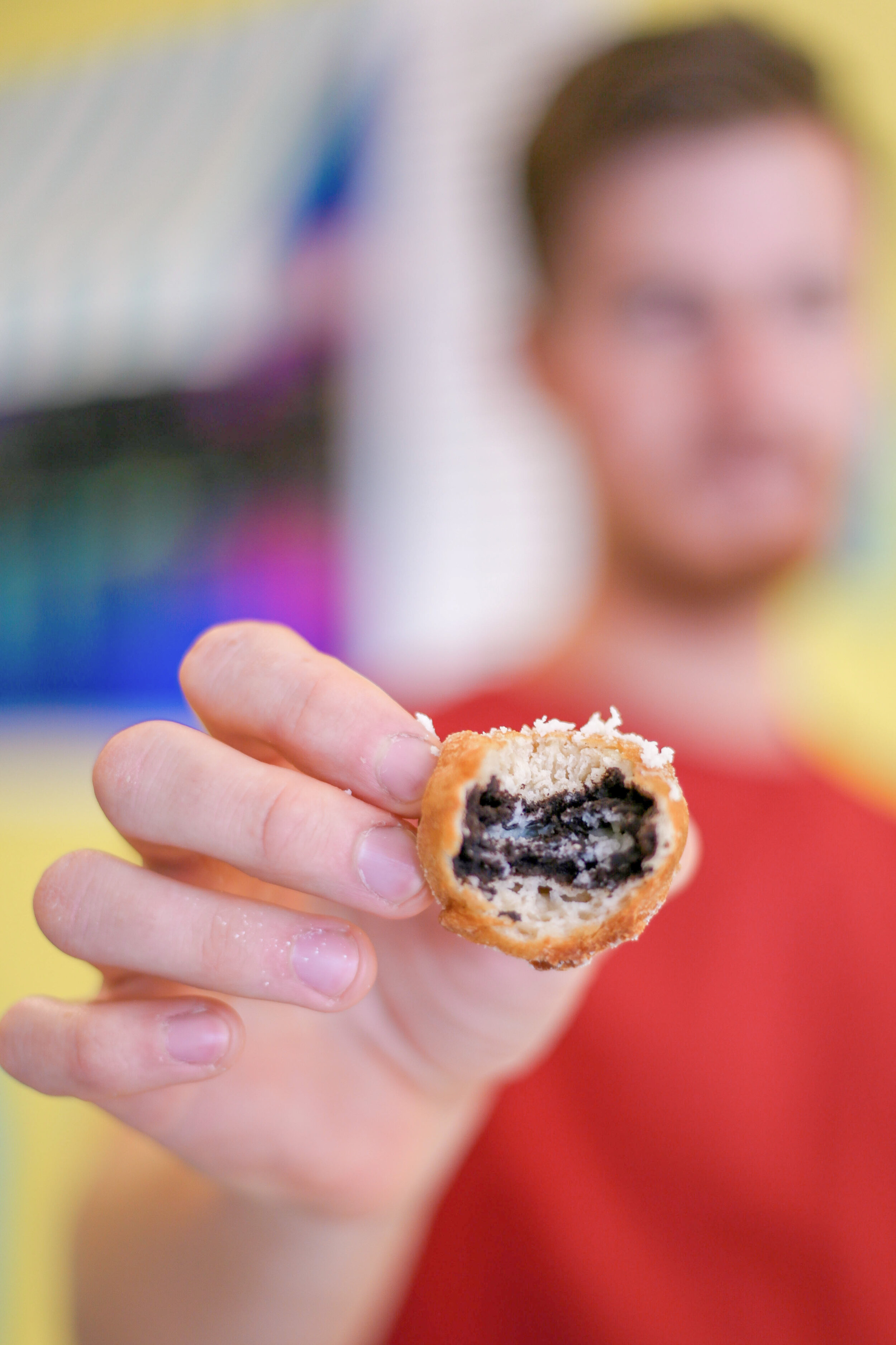 Man holding a Deep Fried oreo bit in half