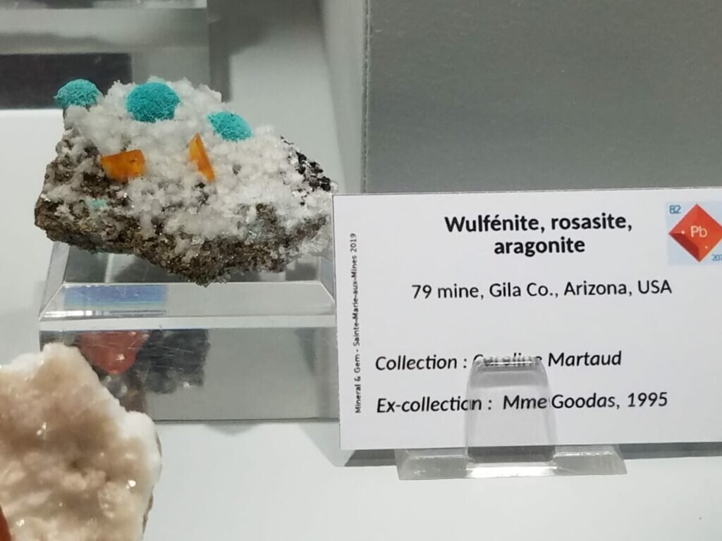 This is just a splendid mineral to behold. Green rosasite and orange Wulfies marching up a hill of snow white aragonite from 79 mine. This is in our top 5 rocks at the show.