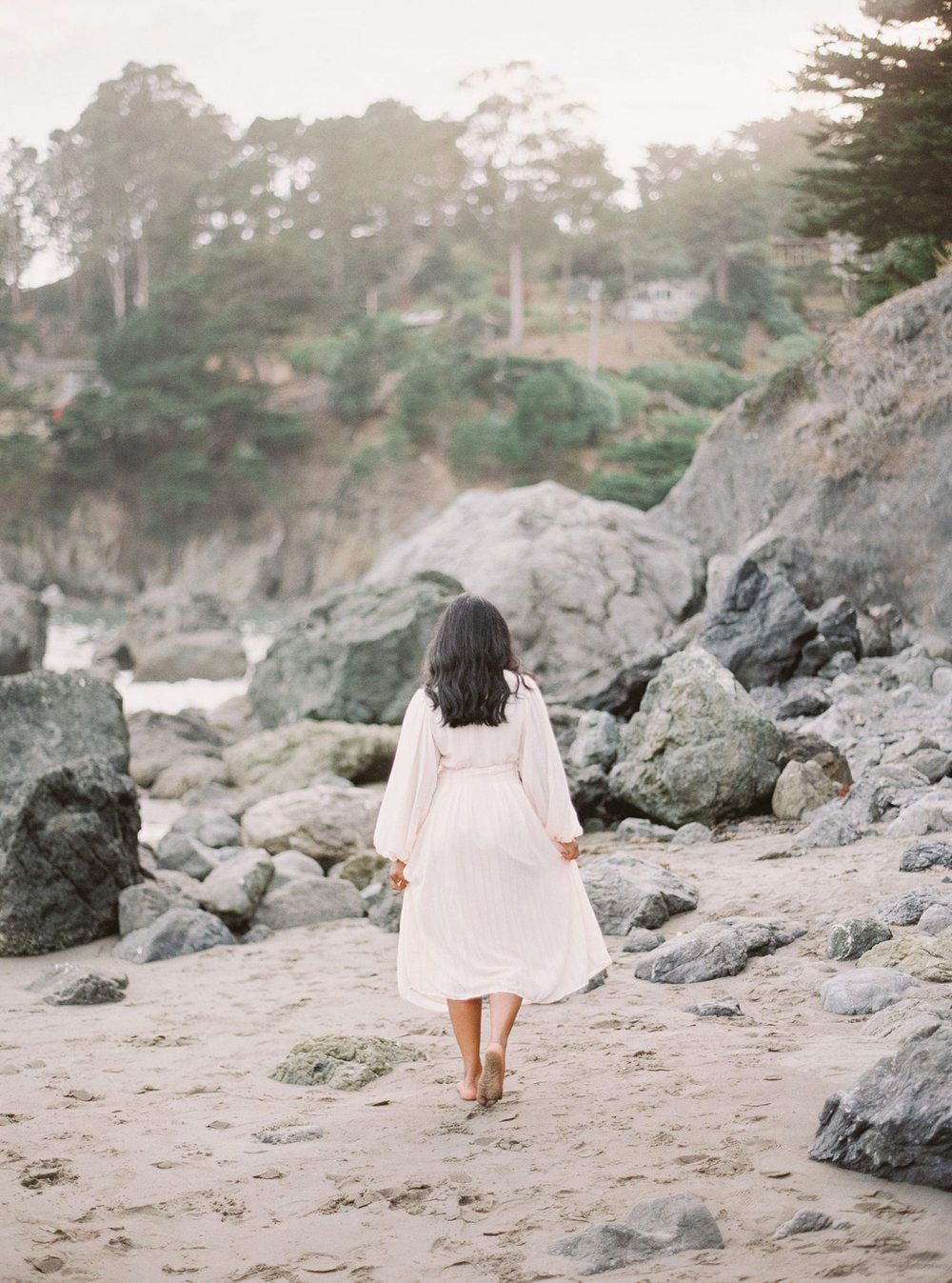 woman in white dress walking along the coast