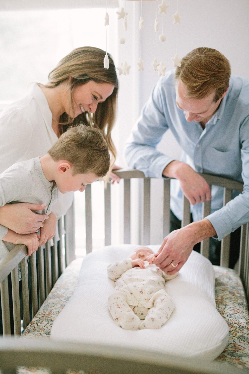 the whole family looking in on newborn baby in crib