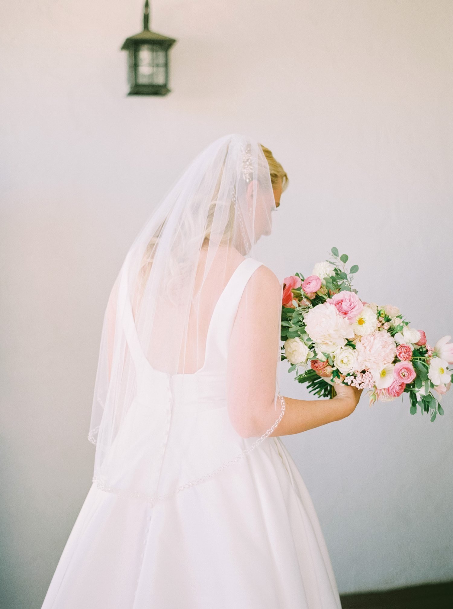 Bride in front of white wall holding flowers