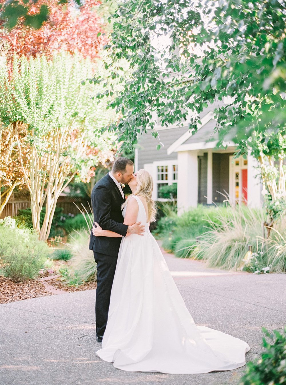 Couple kissing in front of house on their wedding day