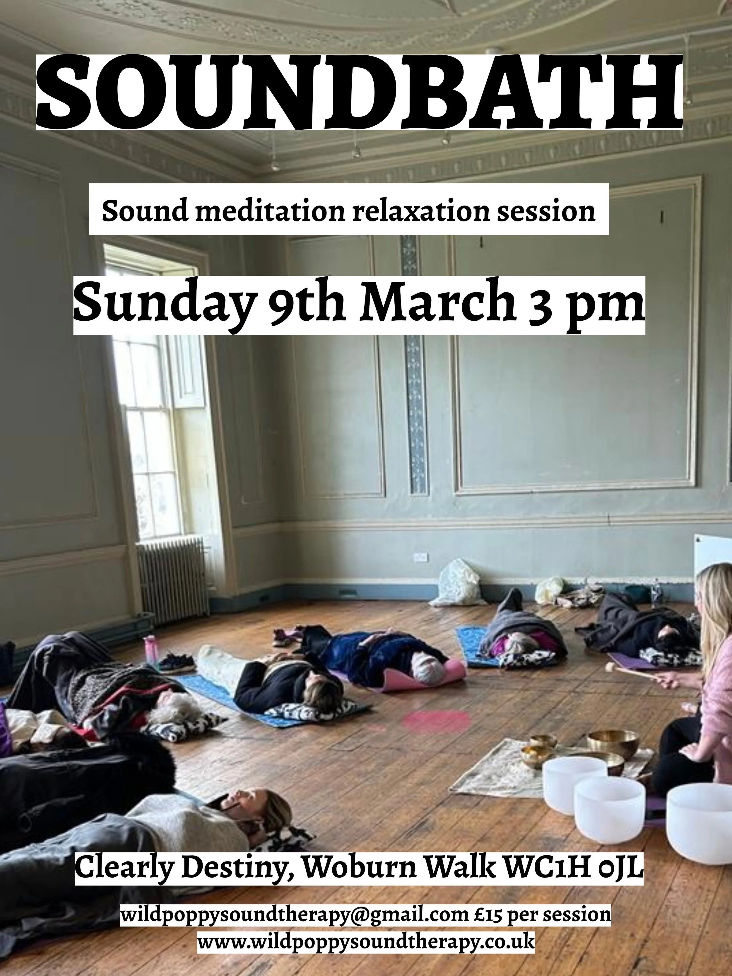 A group of people participating in a sound meditation relaxation session lying on yoga mats in a spacious room with ornate walls and wooden floors. There are singing bowls and a person leading the session seated at the front.