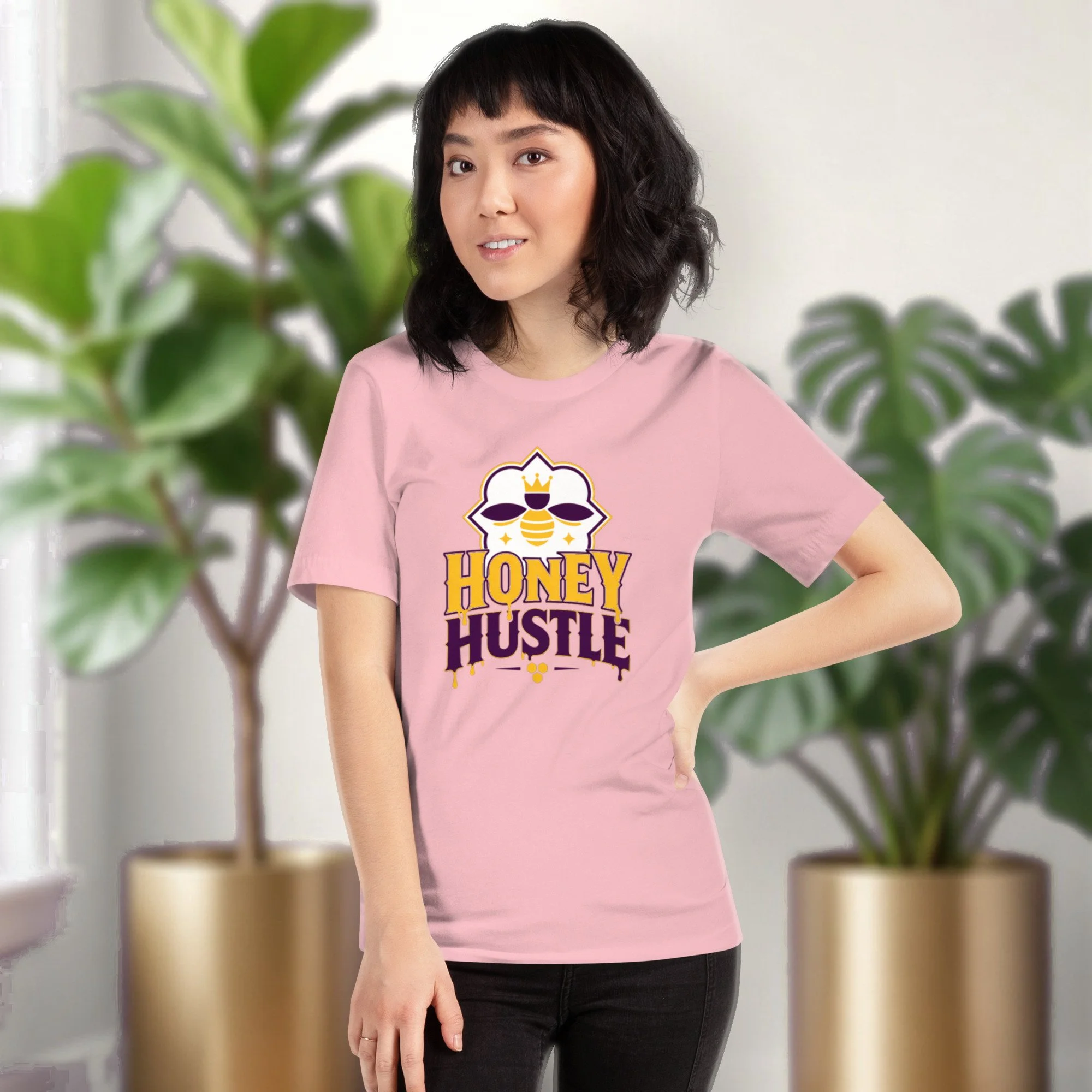 Honey Hustle tee in pink, worn by a model in front of potted plants