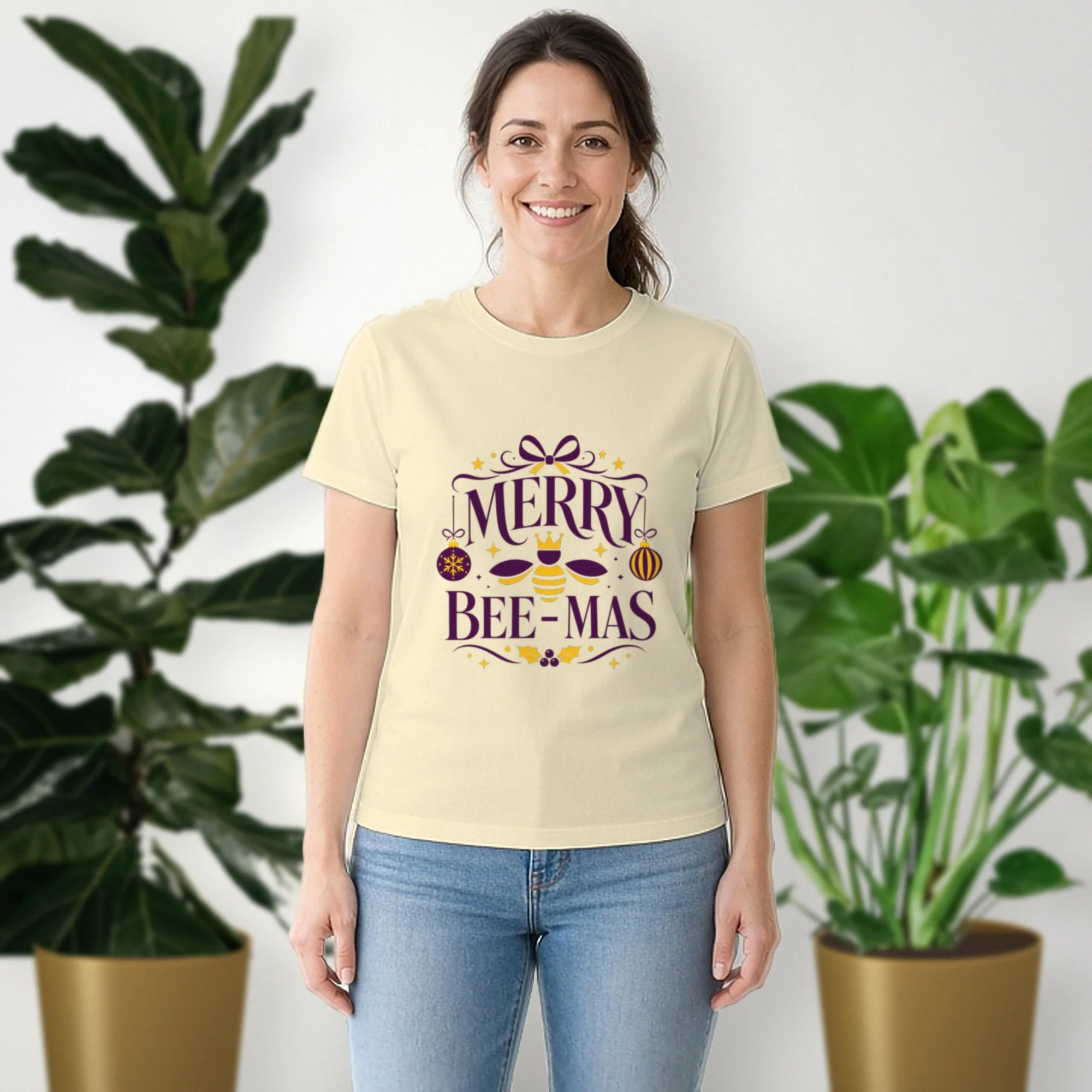 Merry Bee-mas tee in natural, worn by a model in front of potted plants