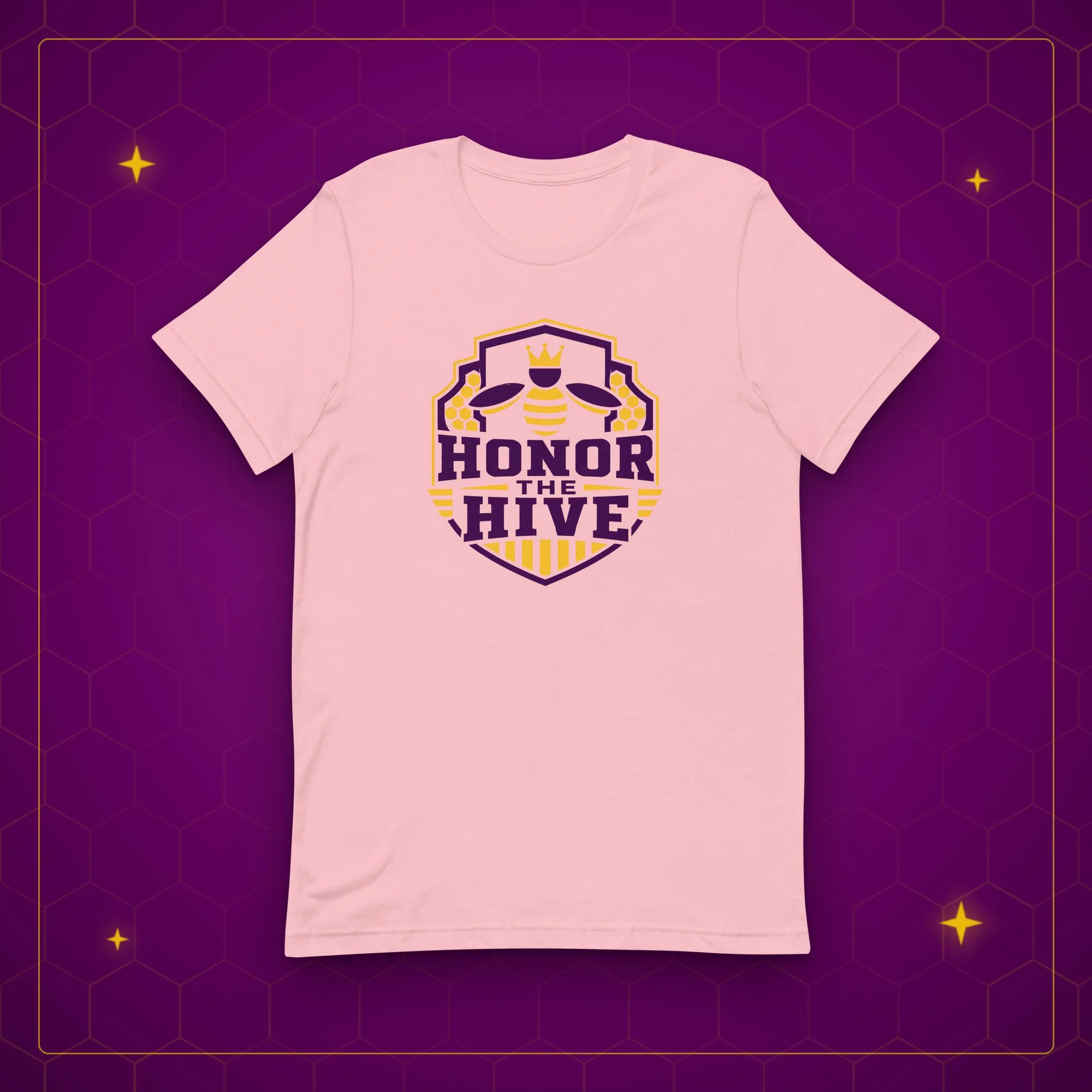 Honor the Hive tee in pink, laid flat on a purple background with gold sparkles