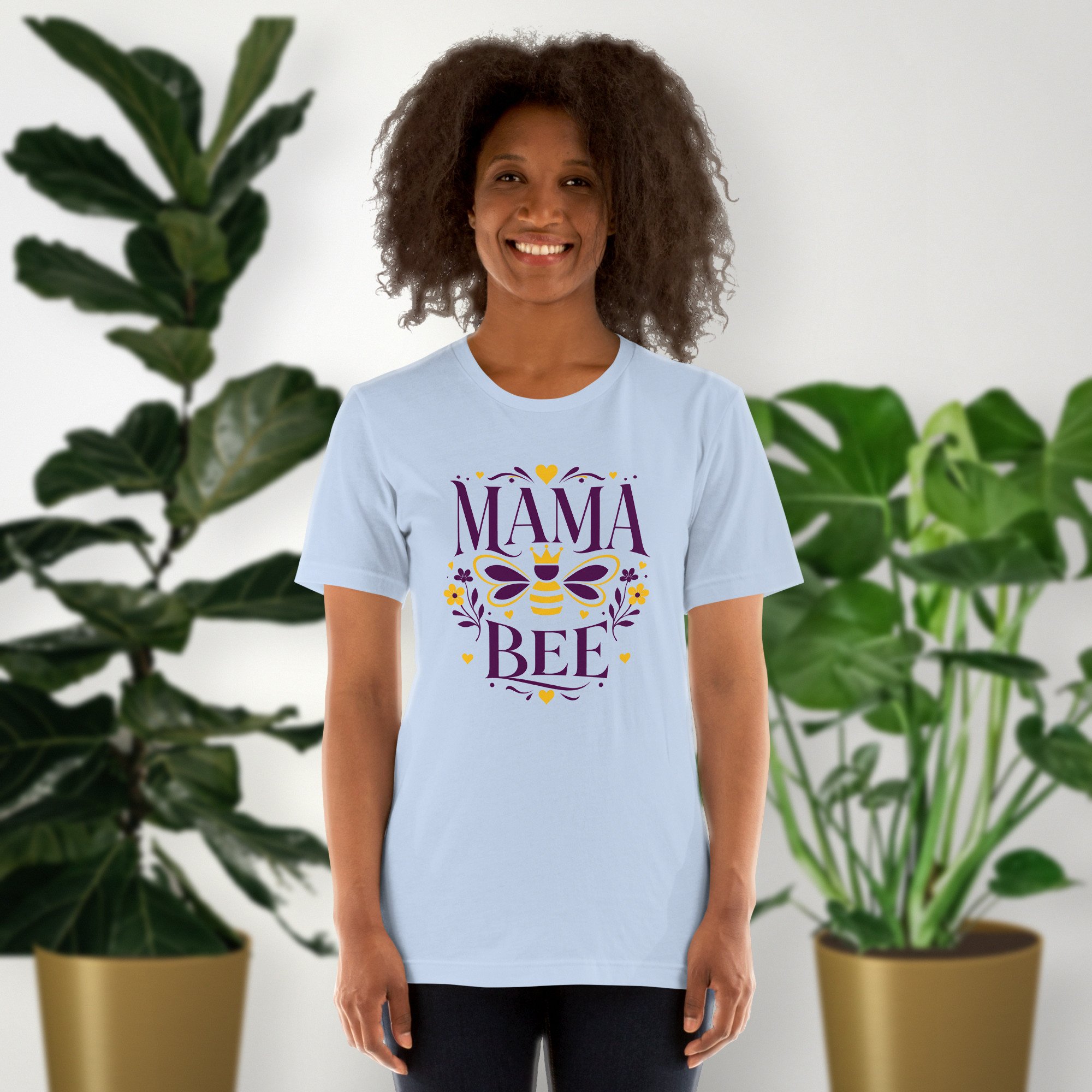 Mama Bee tee in baby blue, worn by a model in front of potted plants