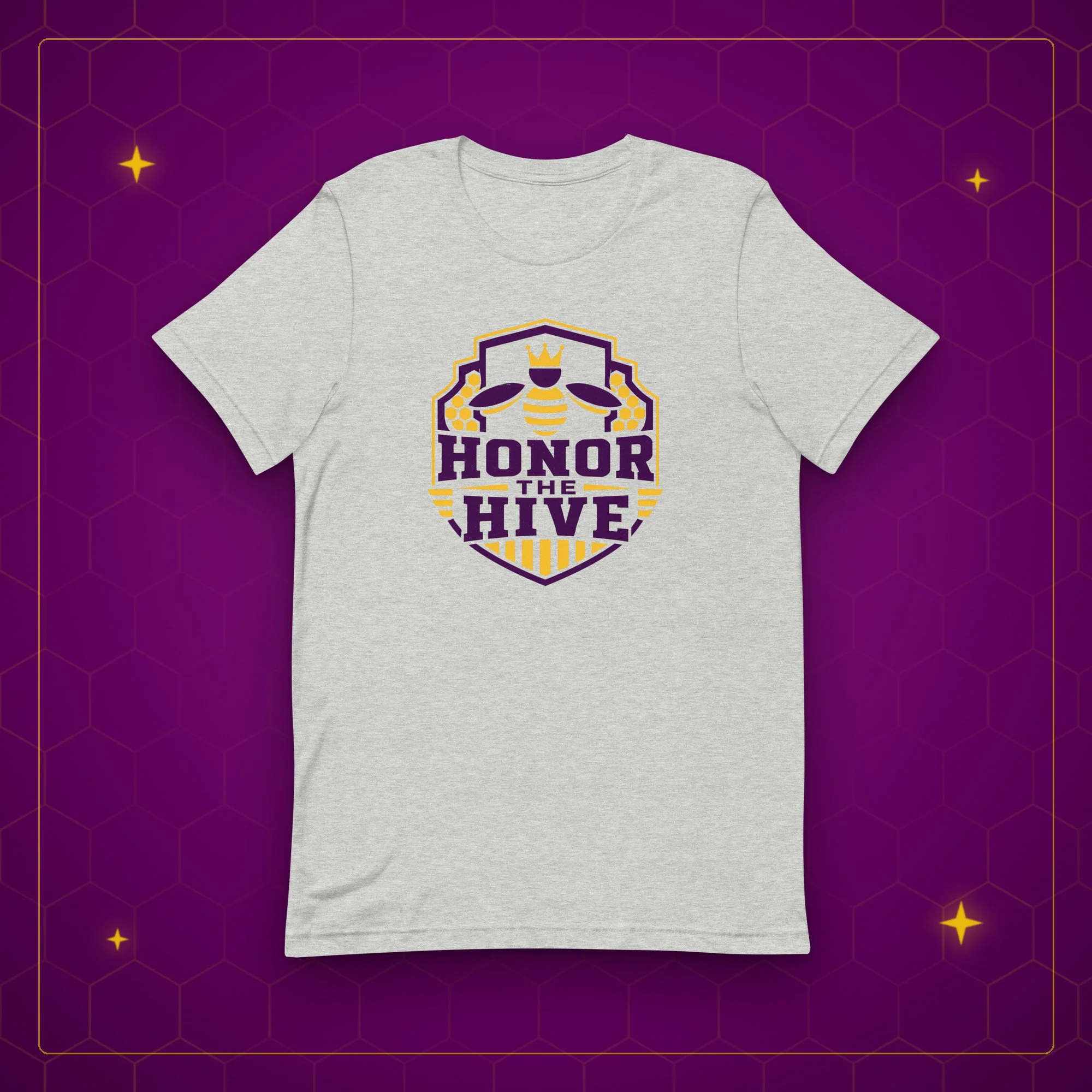 Honor the Hive tee in athletic heather, laid flat on a purple background with gold sparkles