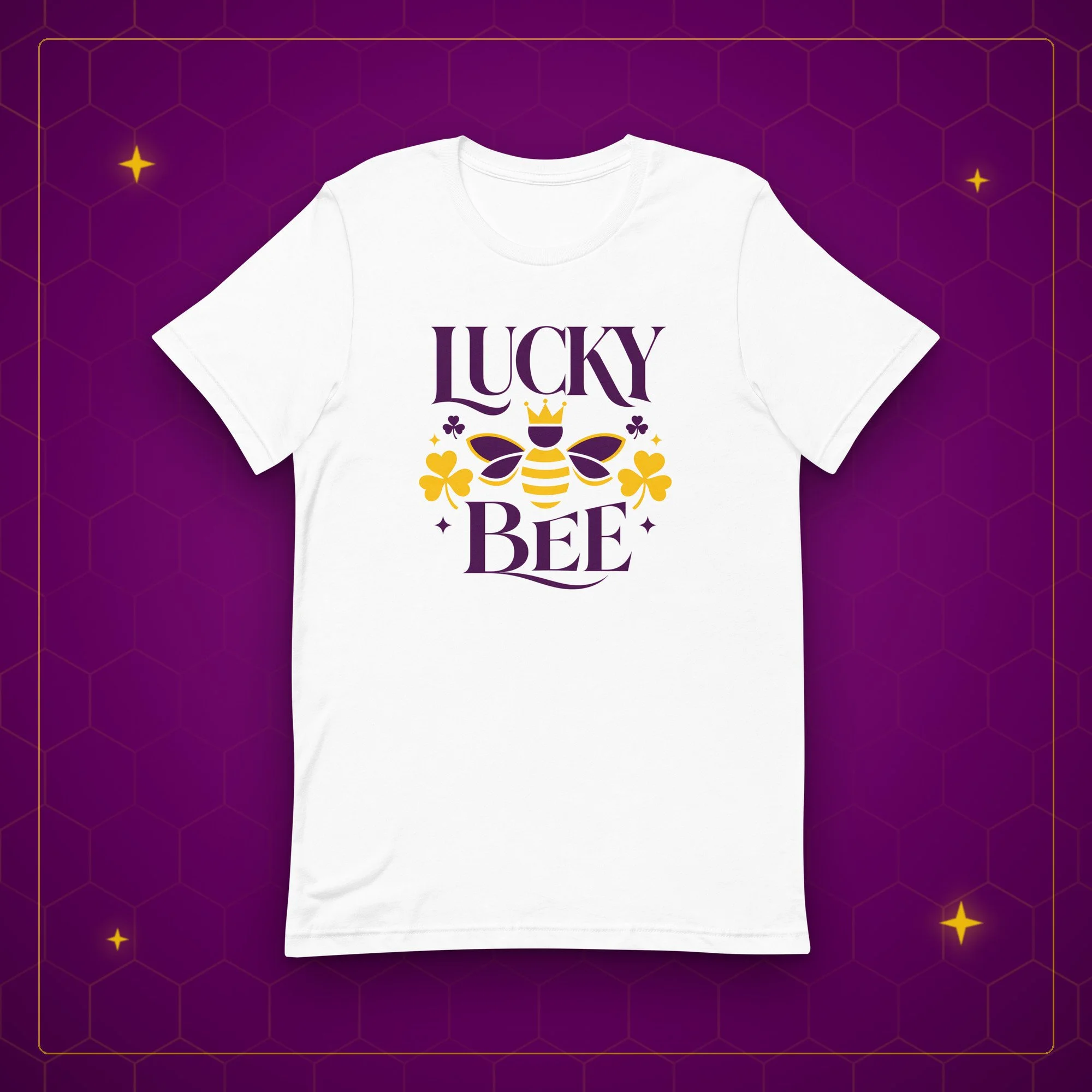 Lucky Bee tee in white, laid flat on a purple background with gold sparkles