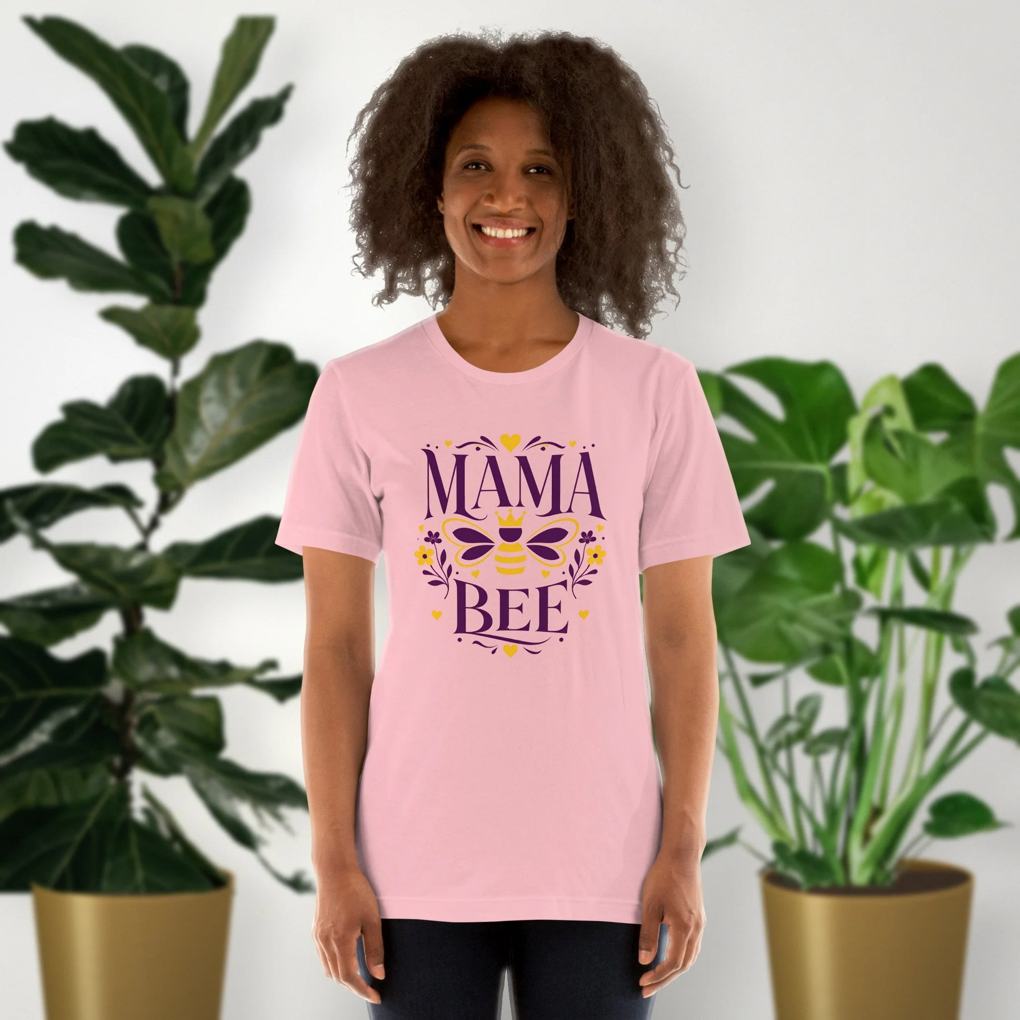Mama Bee tee in pink, worn by a model in front of potted plants