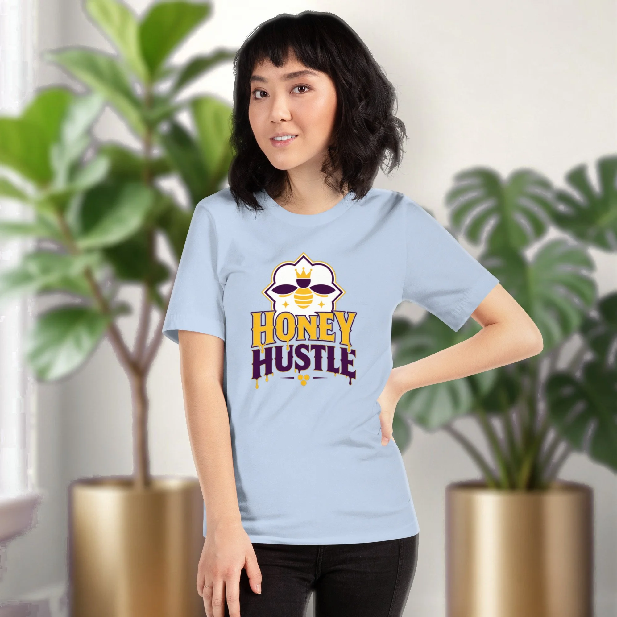 Honey Hustle tee in baby blue, worn by a model in front of potted plants