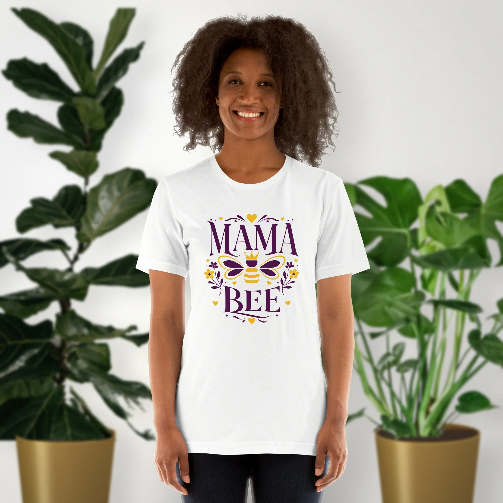 Mama Bee tee in white, worn by a model in front of potted plants