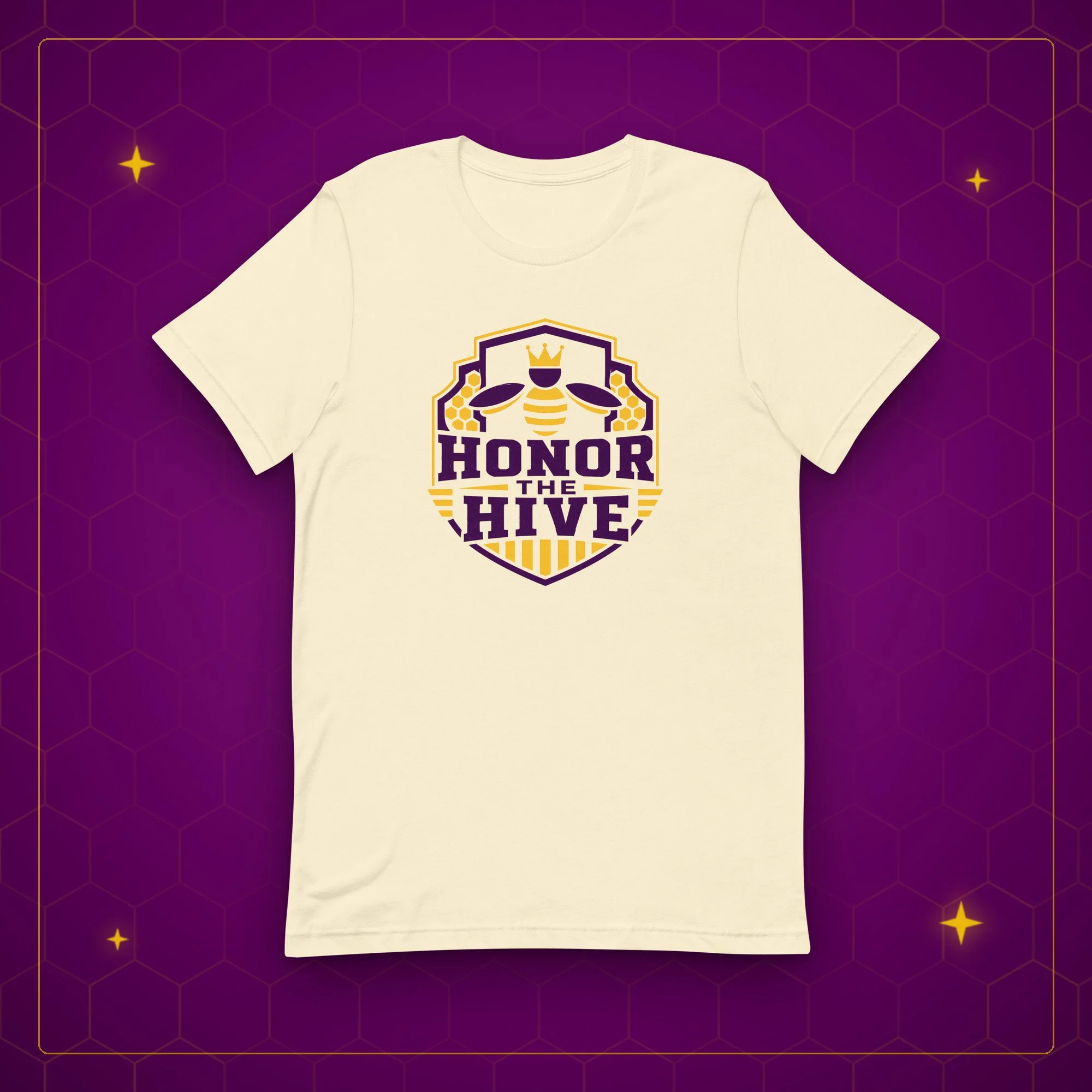 Honor the Hive tee in natural, laid flat on a purple background with gold sparkles
