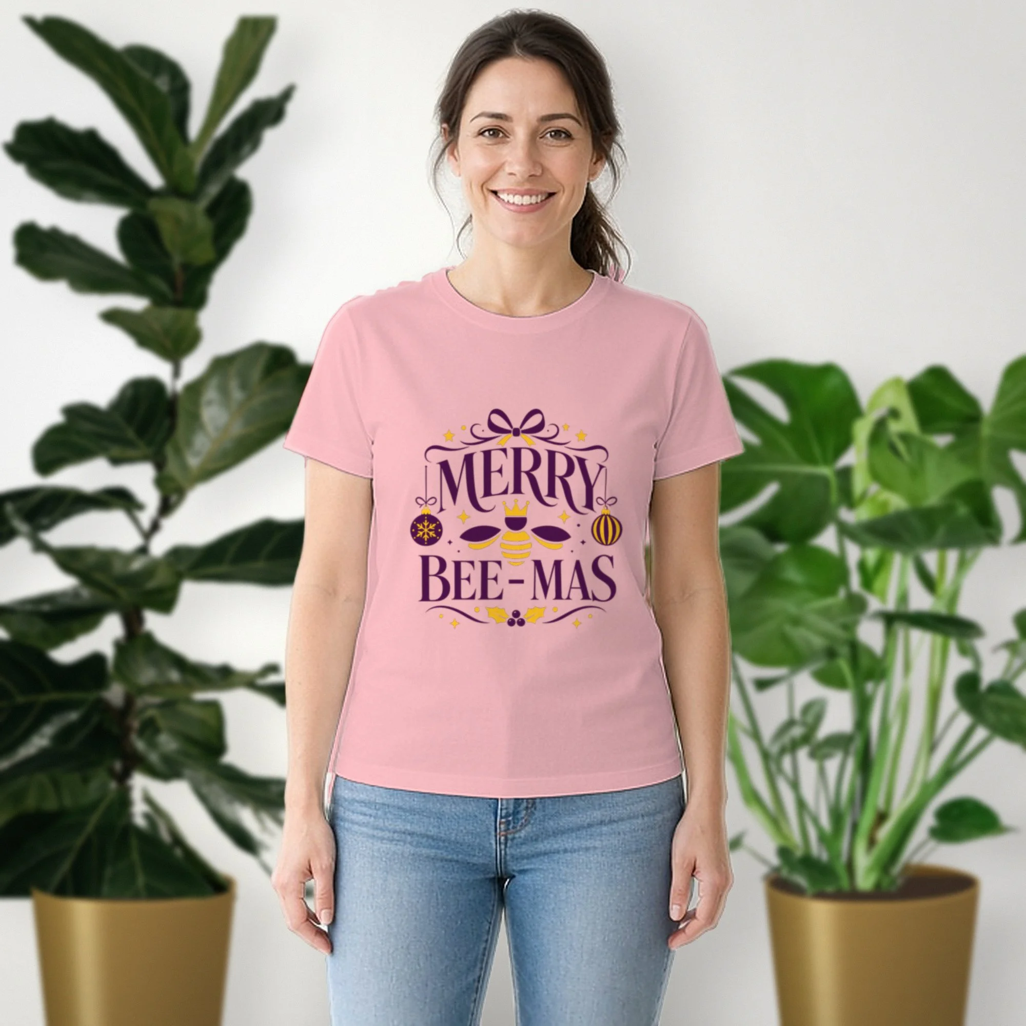 Merry Bee-mas tee in pink, worn by a model in front of potted plants