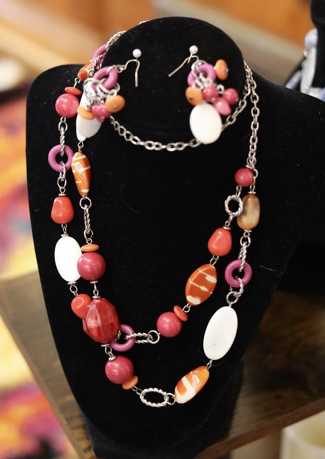 Colorful beaded necklace and earrings on black velvet display