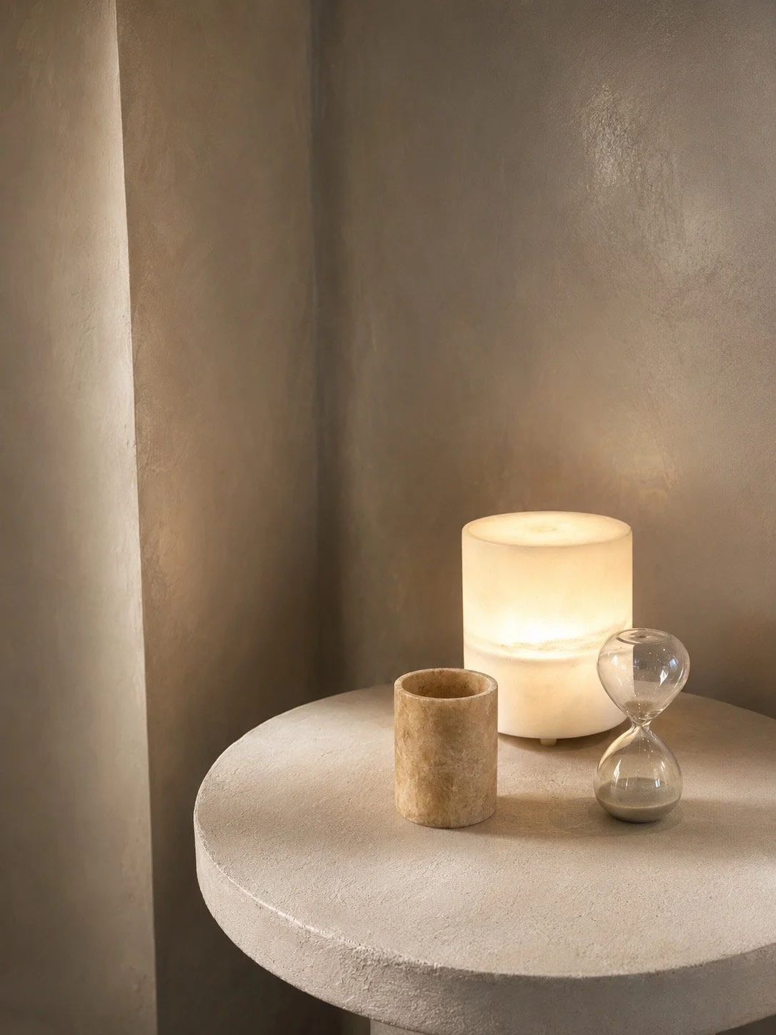 Glowing candle, stone vessel and glass hourglass on a treatment room table at JRAD SKIN.