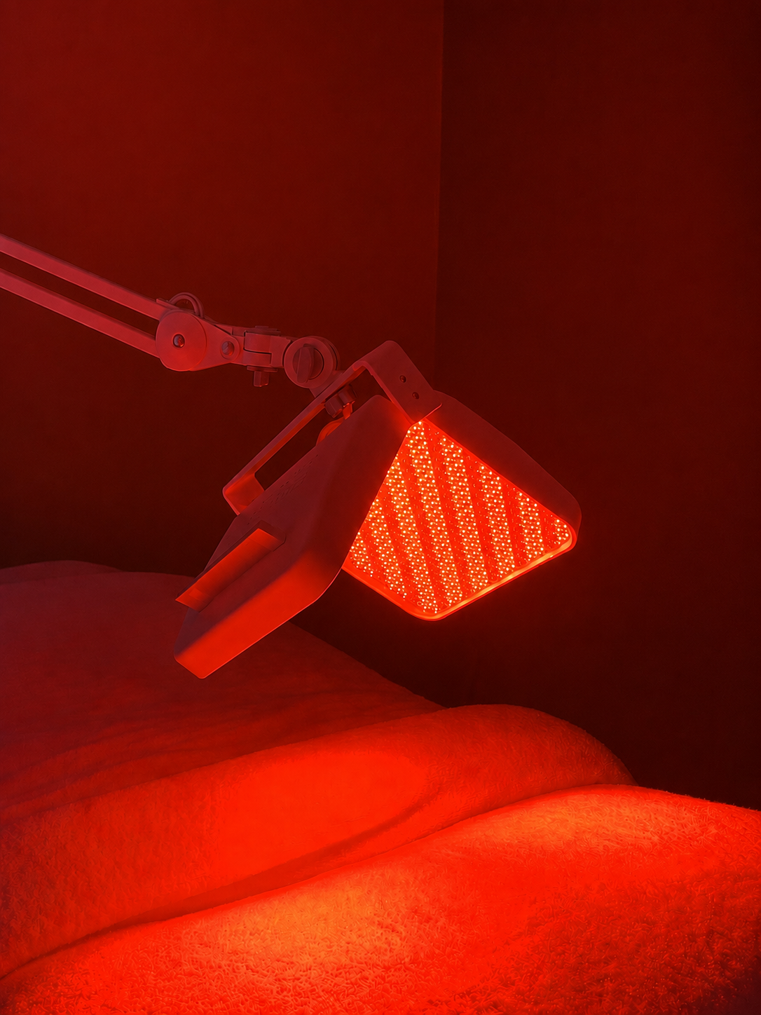 Red LED light therapy device positioned over a treatment bed