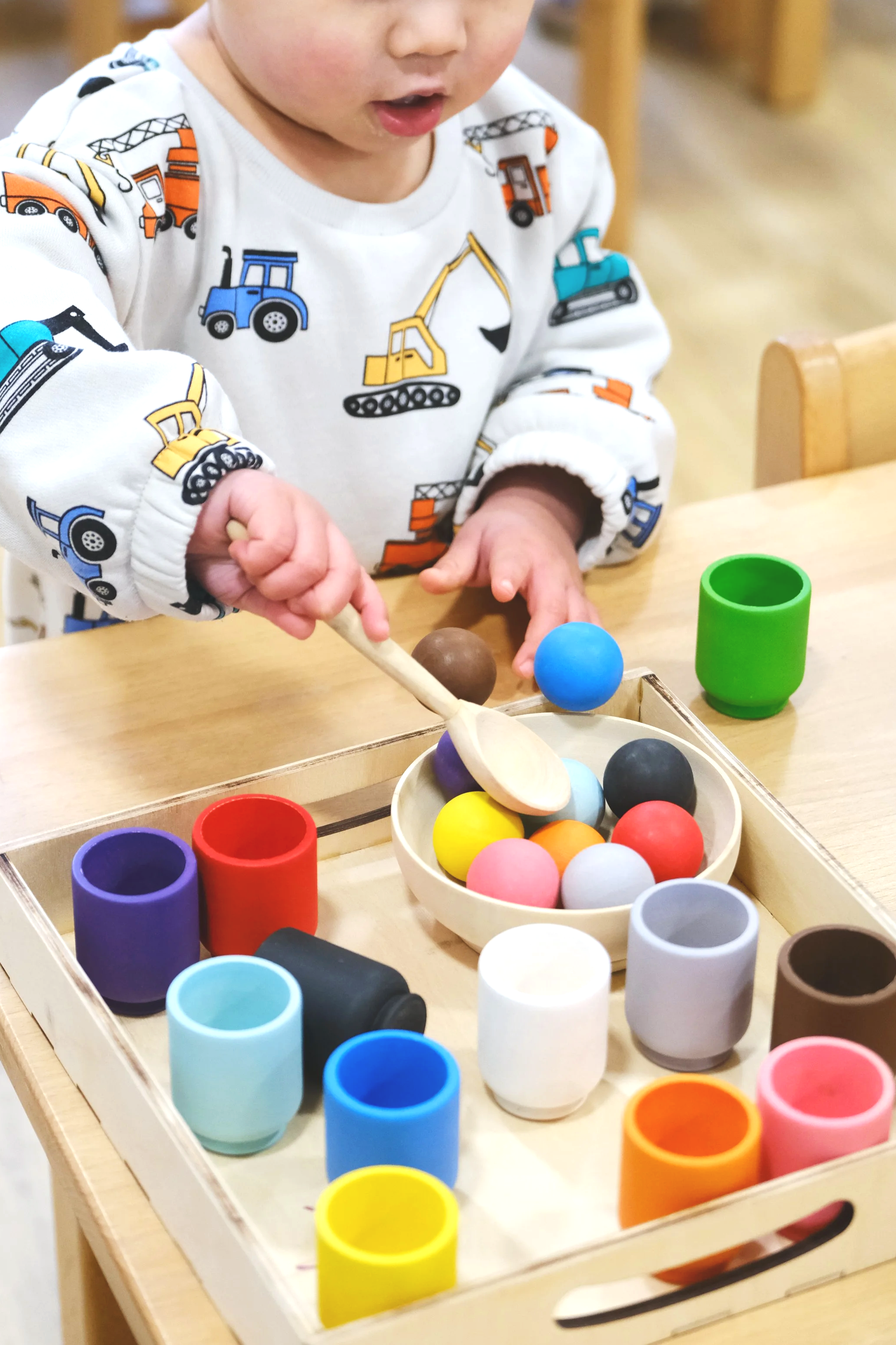 Child picking up wooden balls with spoon