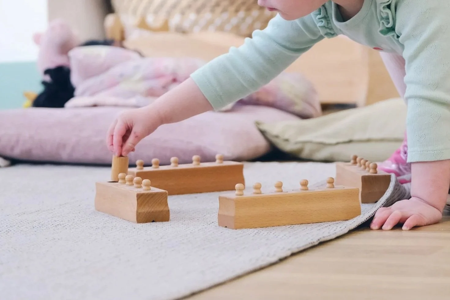 Child reaching over to play with a wooden toy