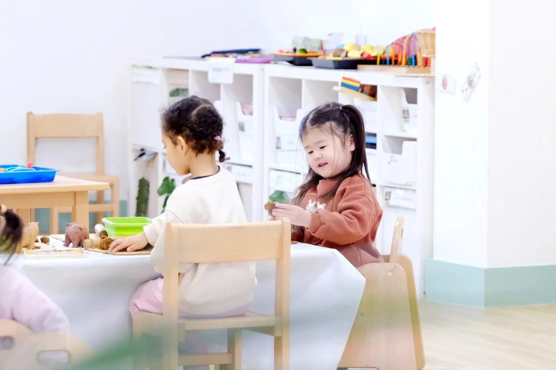 two children sitting down playing with clay on the table