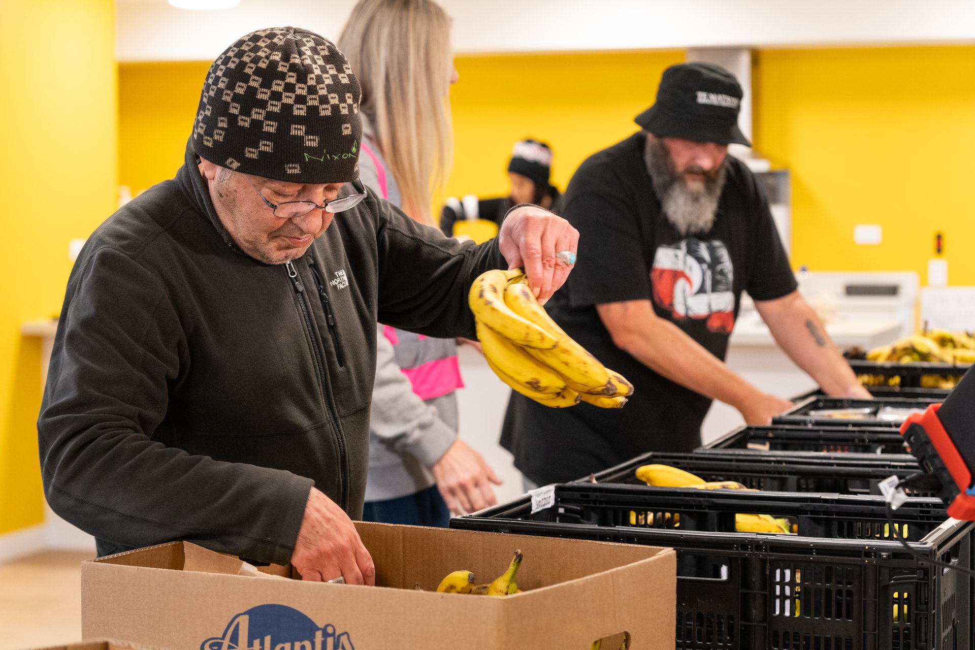man organises box of fresh bananas, donated by KiwiHarvest