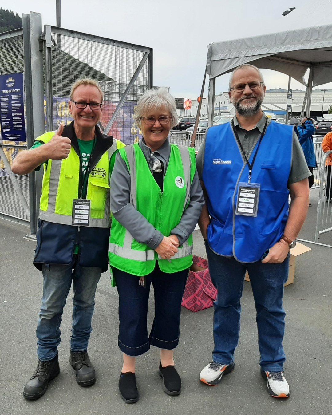 Dunedin KiwiHarvest warehouse supervisor stands smiling with two volunteers ourside the Dunedin Beer Festival