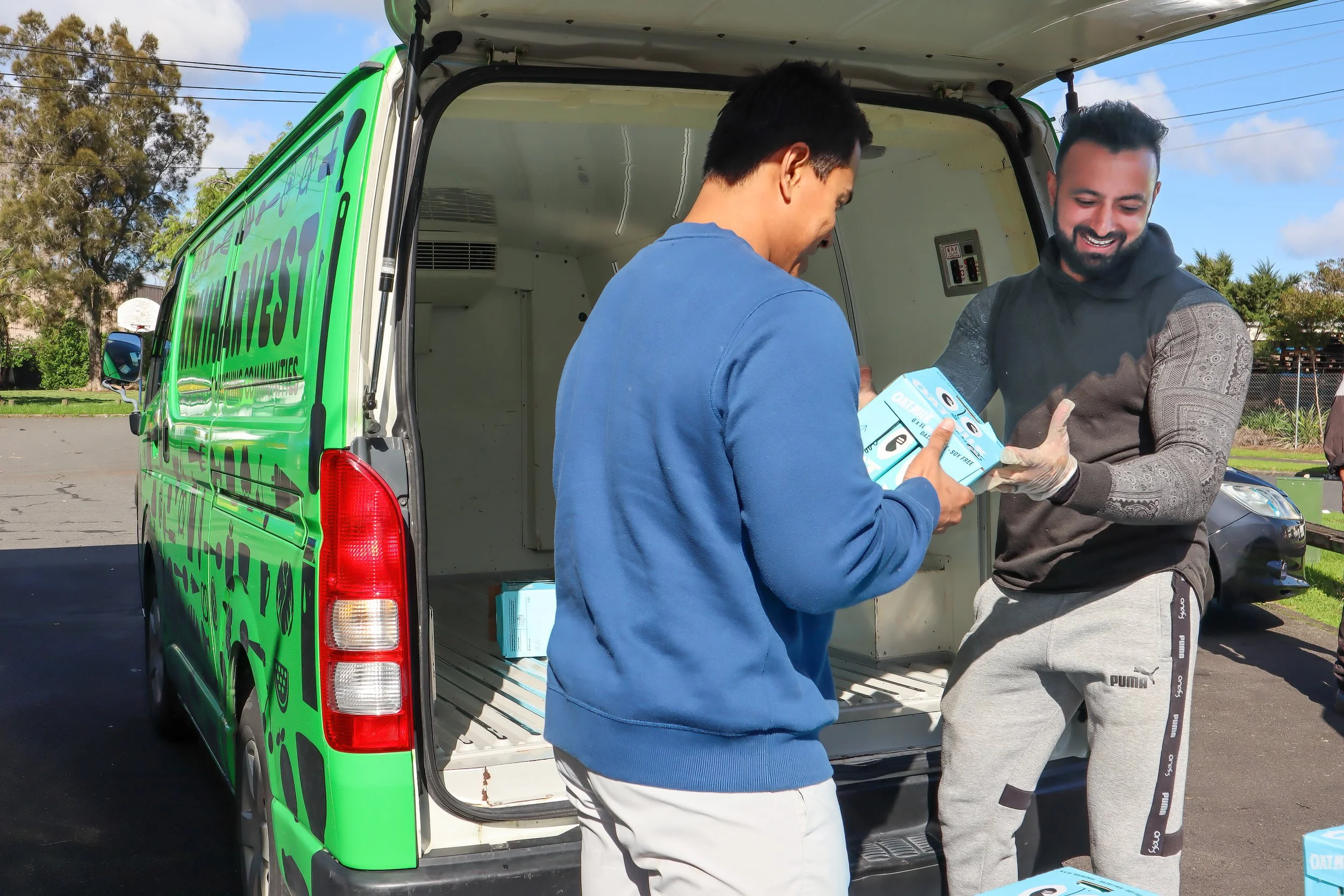 two men packing a KiwiHarvest van with donated goods