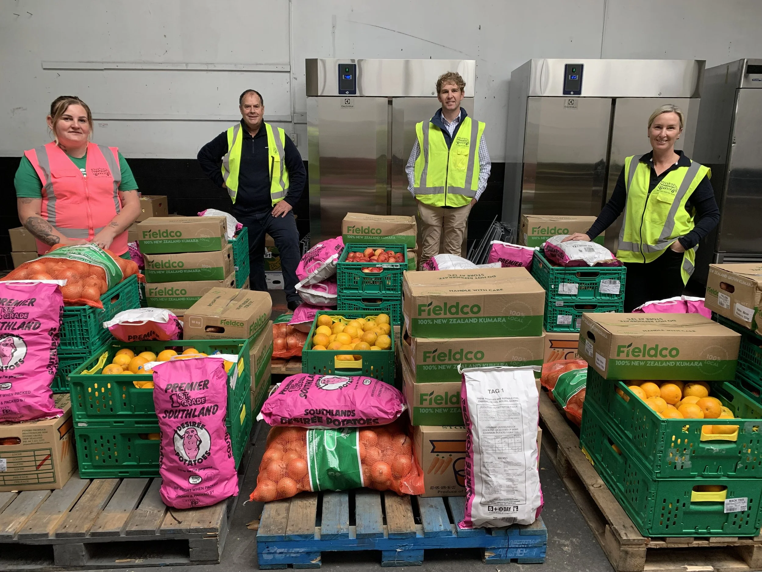 Invercargill Rabobank team stands in the warehouse with fresh produce on pallets