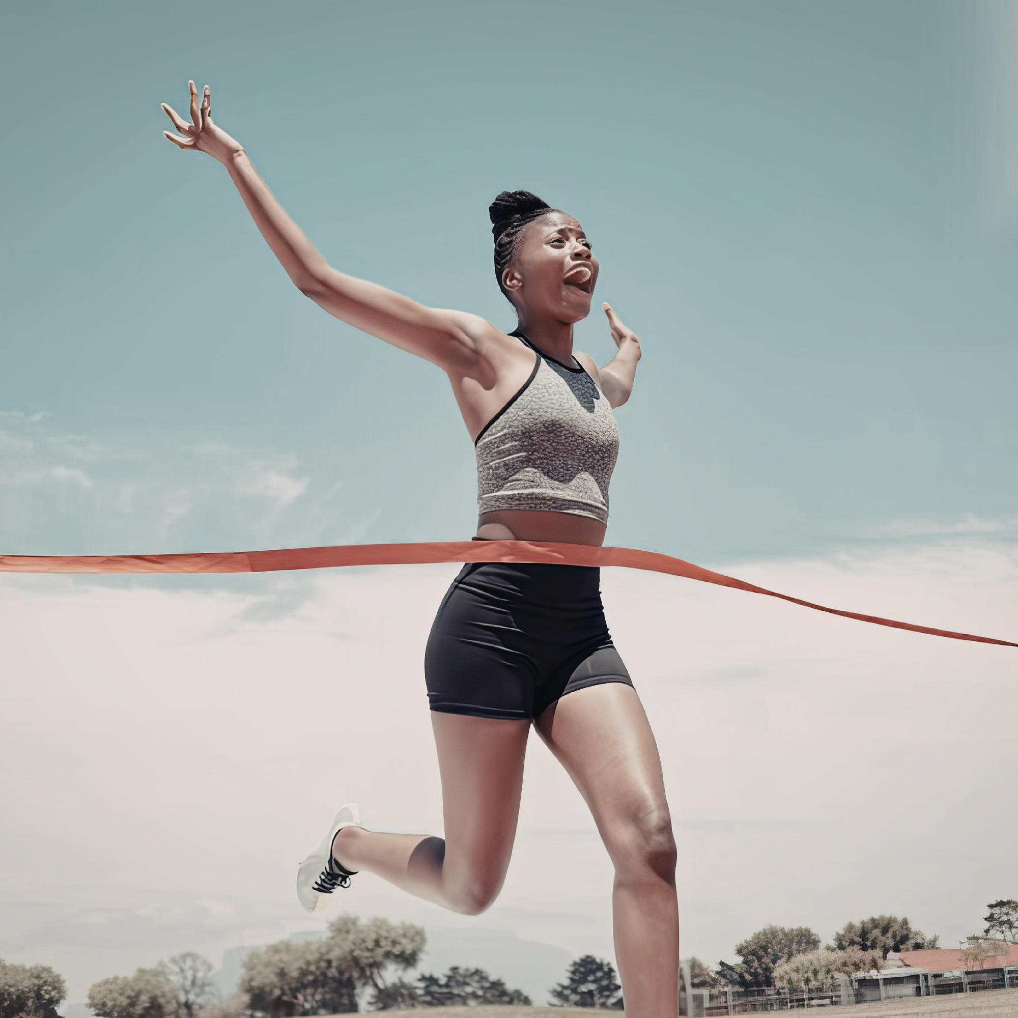Young woman celebrating after running across finish line outdoors on a clear day
