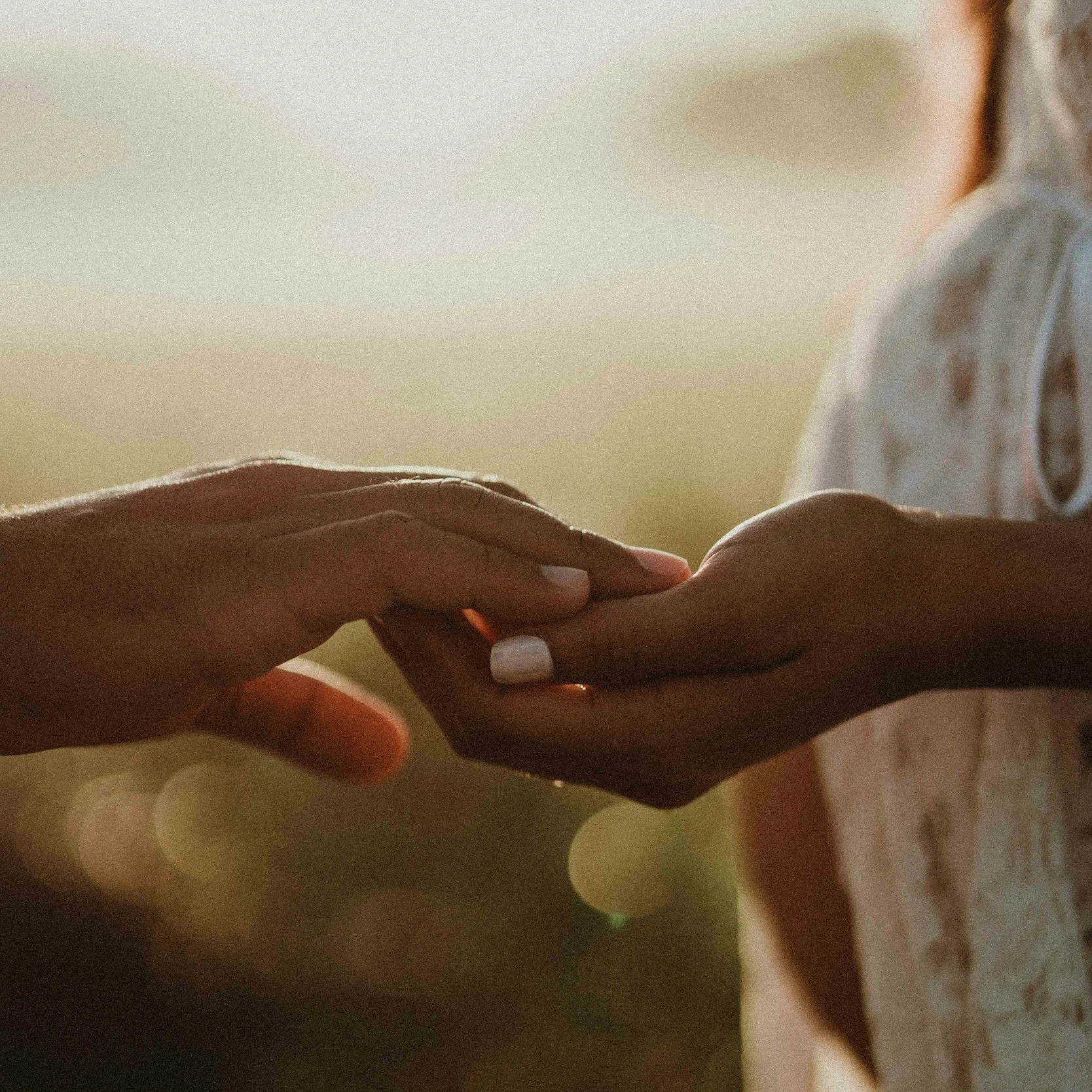 Close-up of two hands gently holding each other, with soft lighting creating a warm and intimate atmosphere.