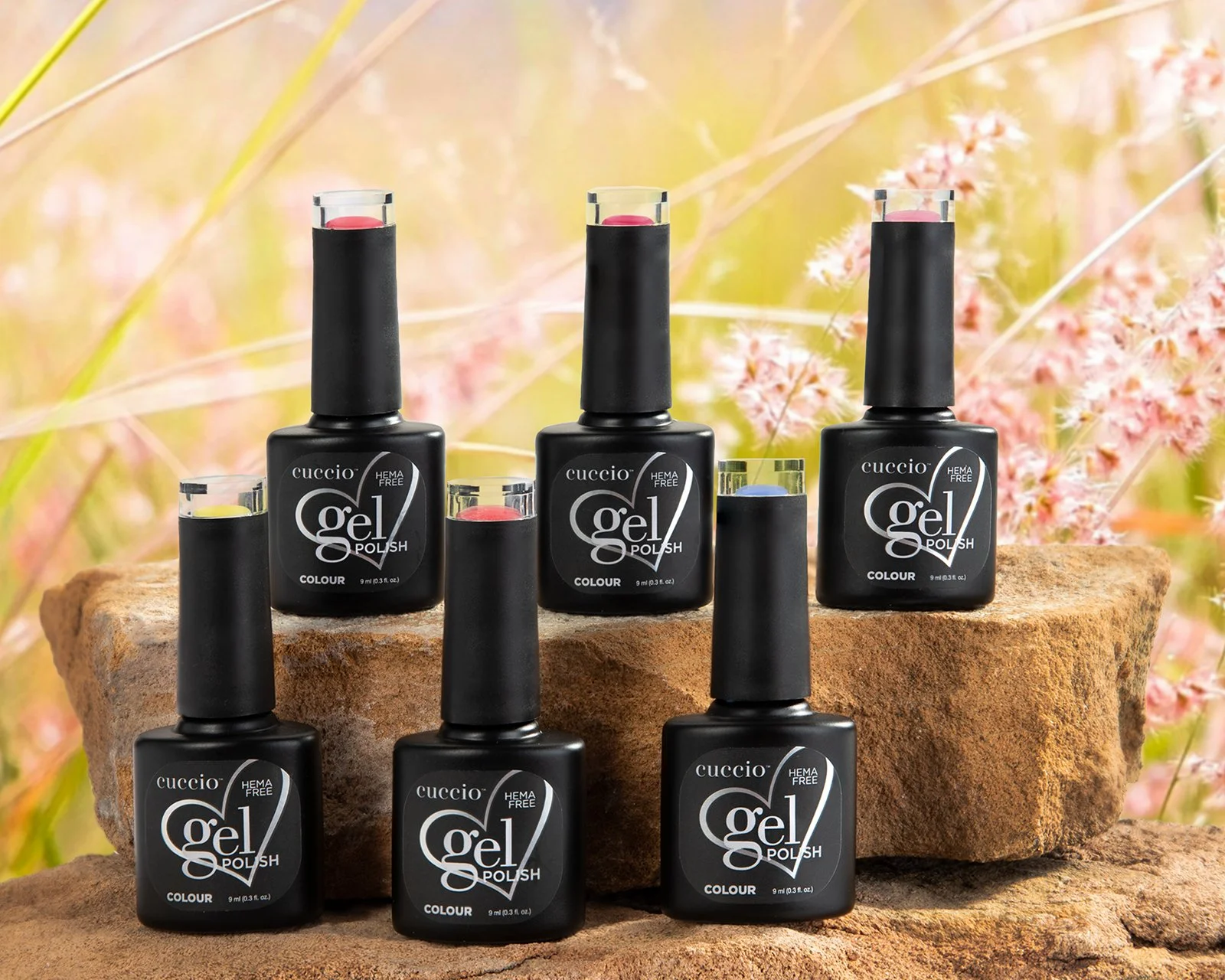 Hero shot of product photography showing a range of cuccio nail gel bottle positioned on stone blocks onto a summer floral background
