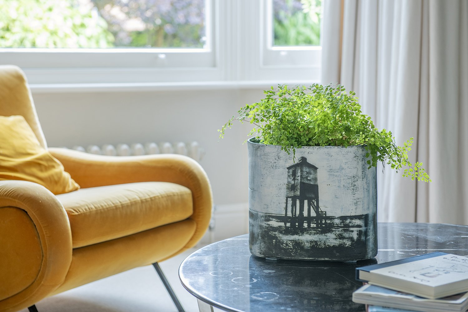 location lifestyle product photography showing a ceramic vases by fotoceramica on a glass table with soft furnishing and window looking onto a garden the background