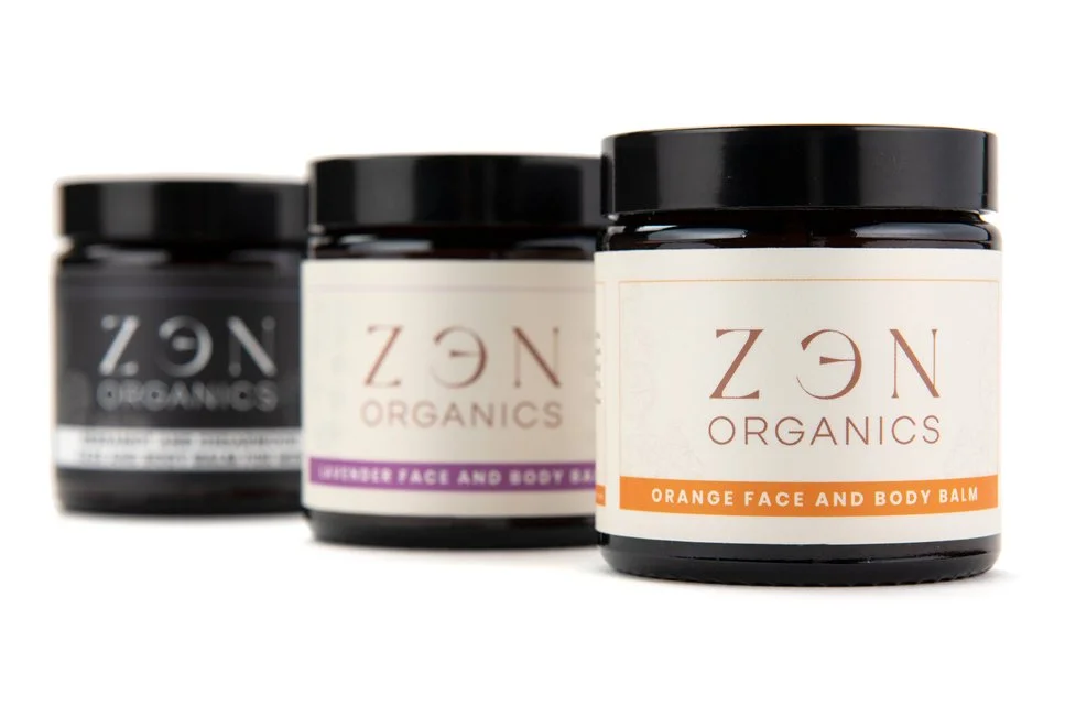 Three jars of ZEN Organics face and body balms arranged in a row, with the front jar labeled 'Orange Face and Body Balm' in focus.