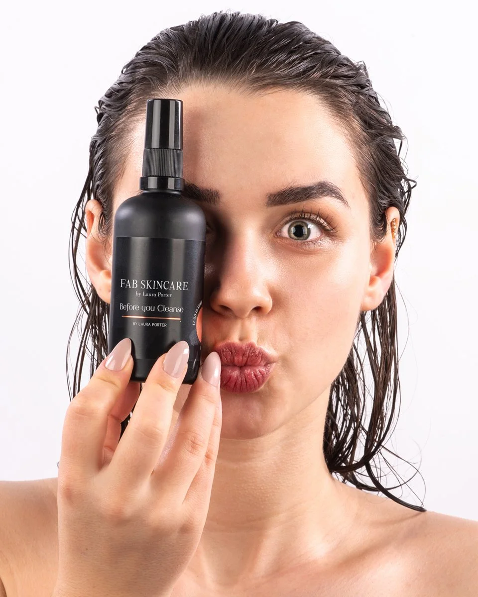 lifestyle product photography shot for FAB face and body skincare product with young dark haired model with wet hair wide eyes and pouting lips holding product up to face  