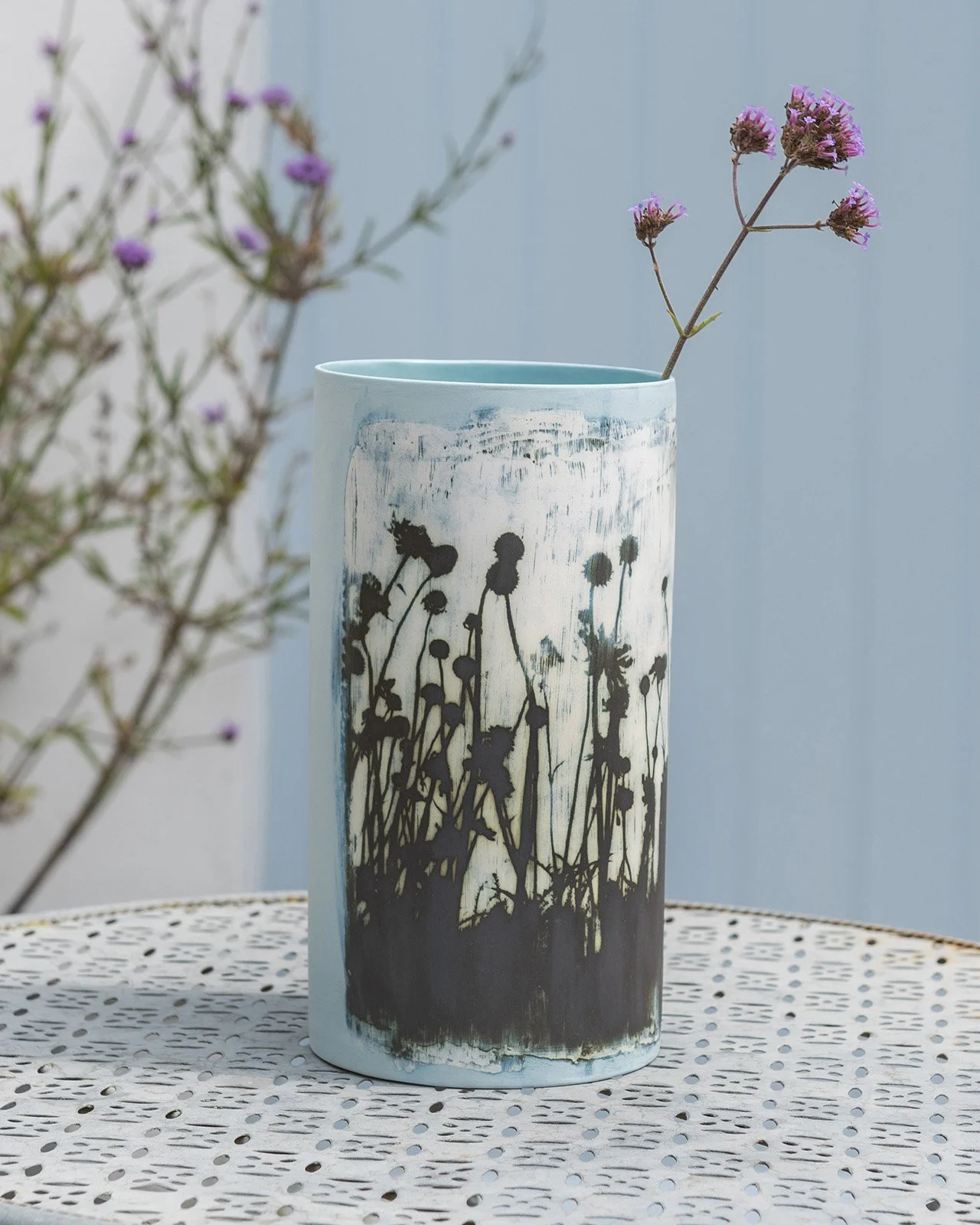 location lifestyle product photography of a ceramic vase by fotoceramica on a table with a blue door in the background