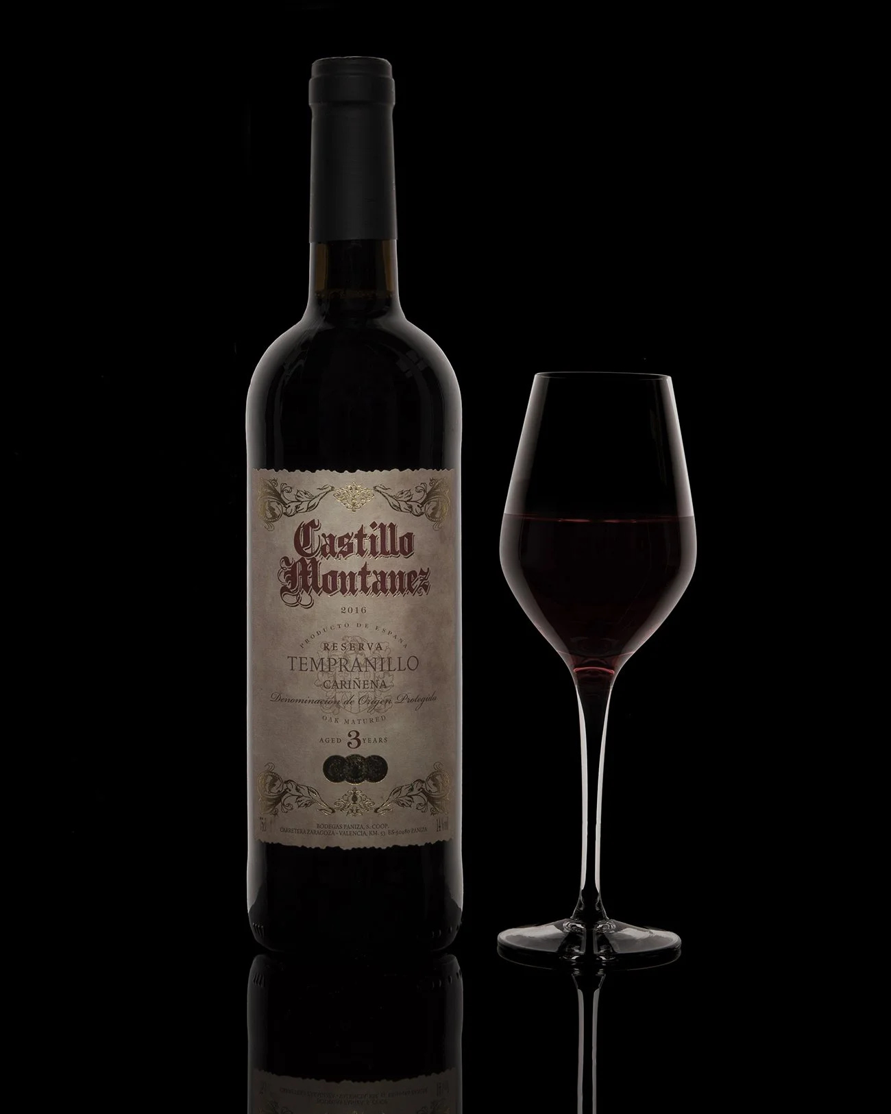 product hero photography showing a Bottle of red wine and a wine glass filled with red wine against a black background