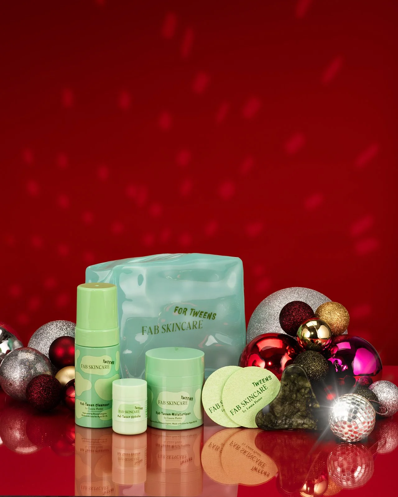 festive product hero photography shot showing a full range of products by FAB tween Skincare with christmas decorations on a graduated red background